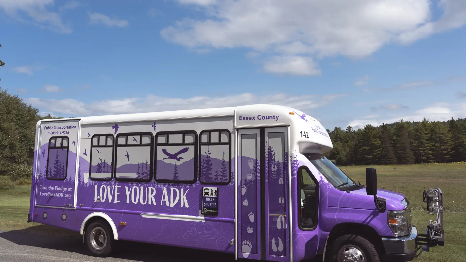 A side view of the purple, ADK-themed hiking shuttle bus.