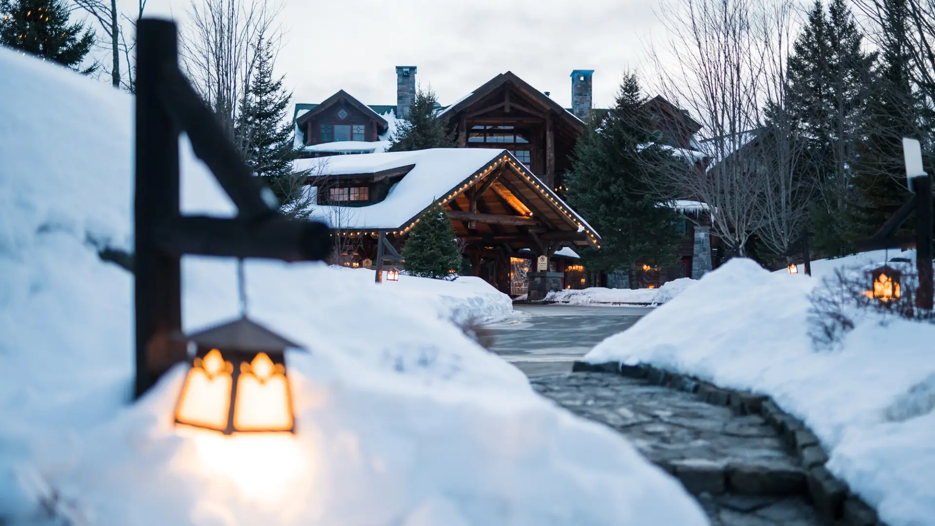 A rustic hotel lodge is tucked amidst snowy lawns.