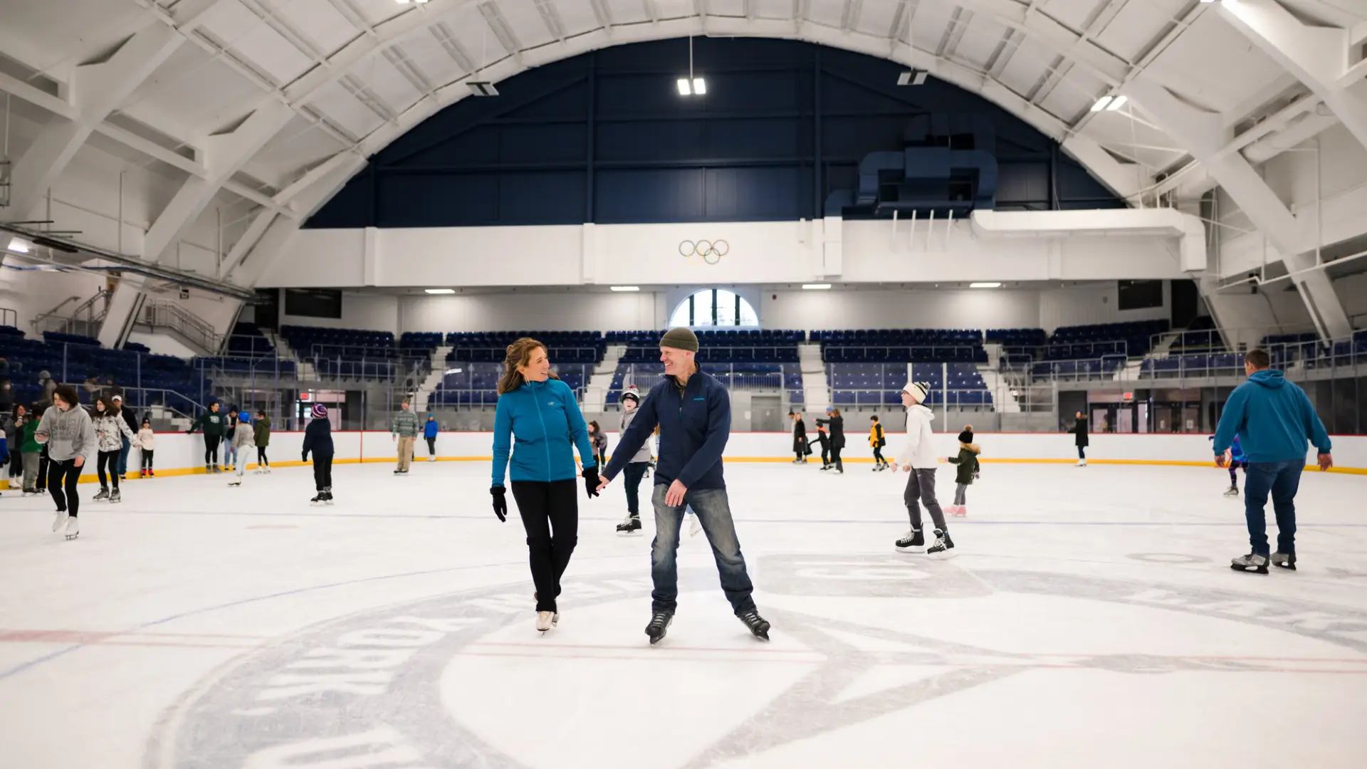 a couple skates in the middle of an ice skating rink.