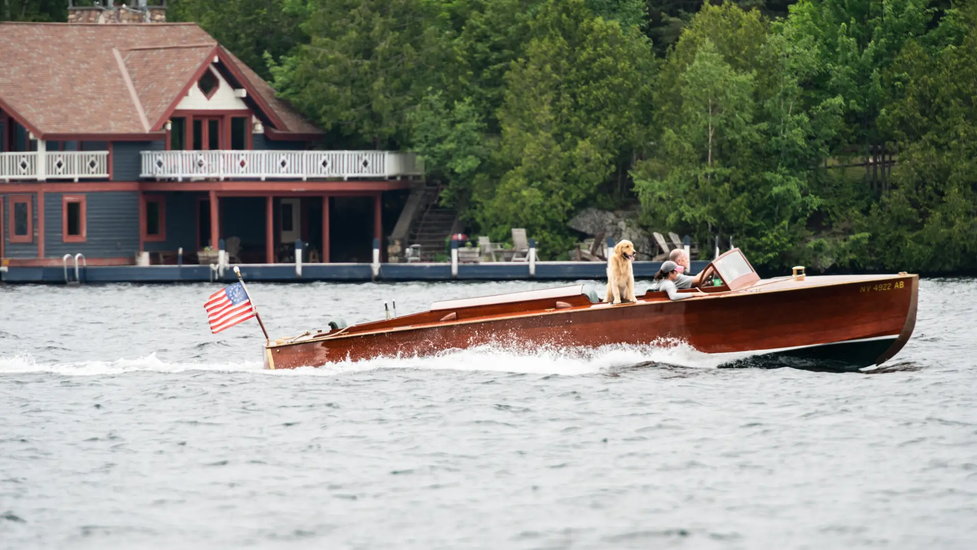 A couple drives a Chris-Craft out on a lake.