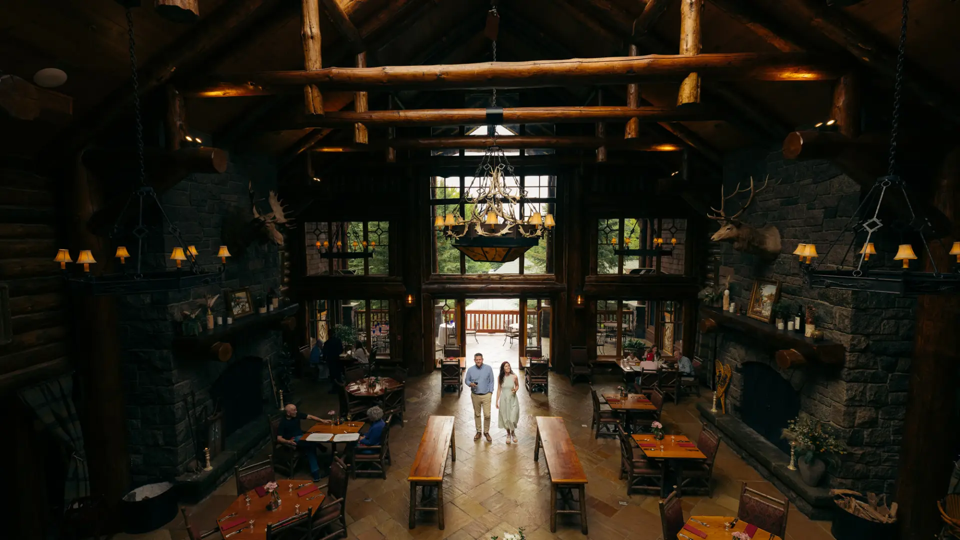 A man and woman walk into a luxury lodge dining room.