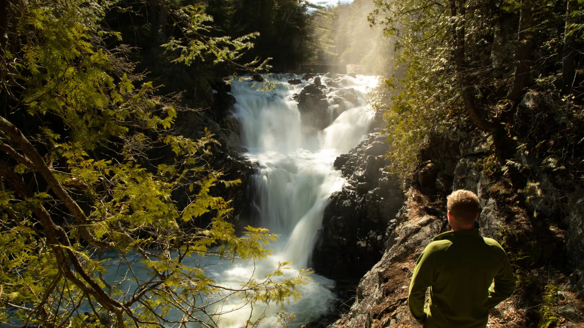 A hiker looks at a large waterfall