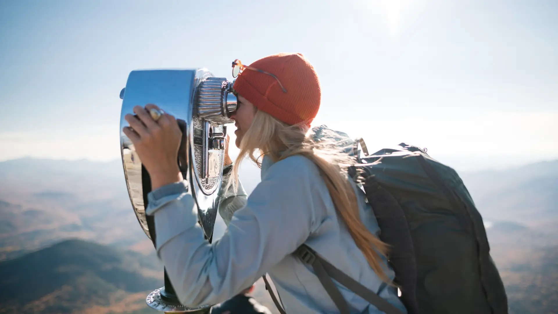 A young woman on the summit of Whiteface Mountain looks through coin operated binoculars