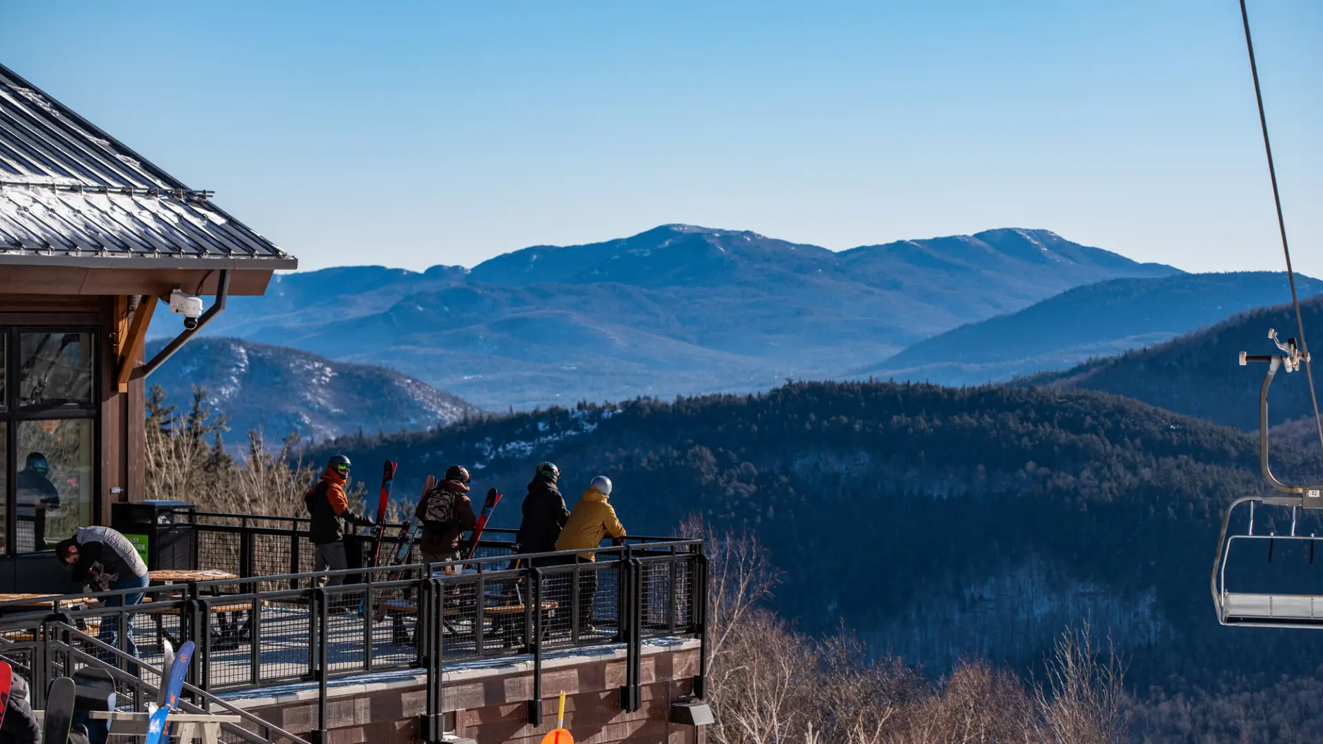 Group of friends hangs out on the porch of the midstation lodge with the mountains in the background
