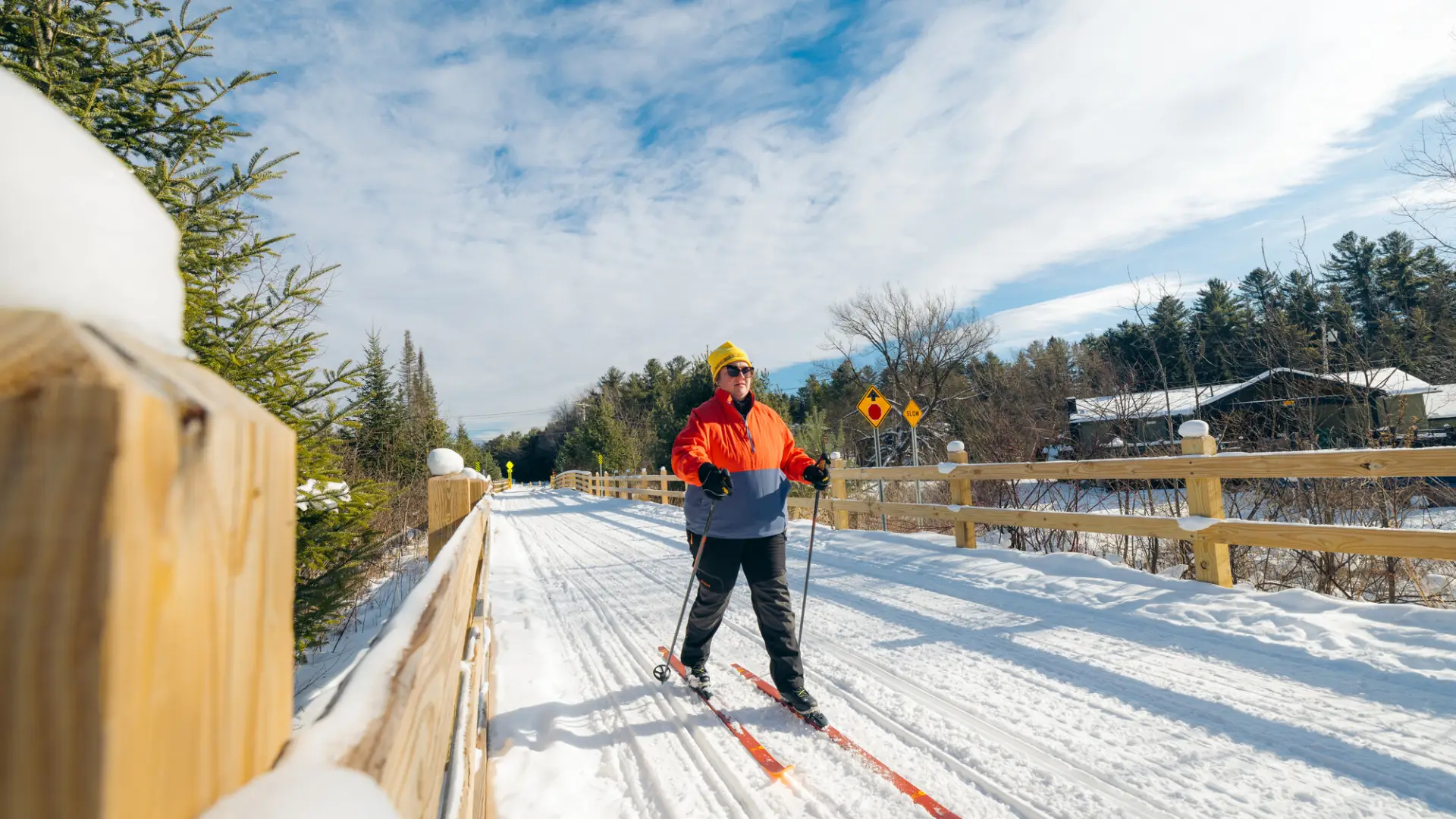 Woman cross-country skiing over long bridge on Adirondack Rail Trail on nice winter day