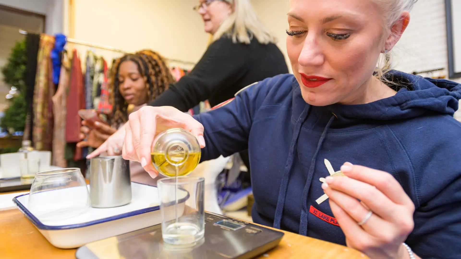 A woman pours oil into a glass jar in a shop.