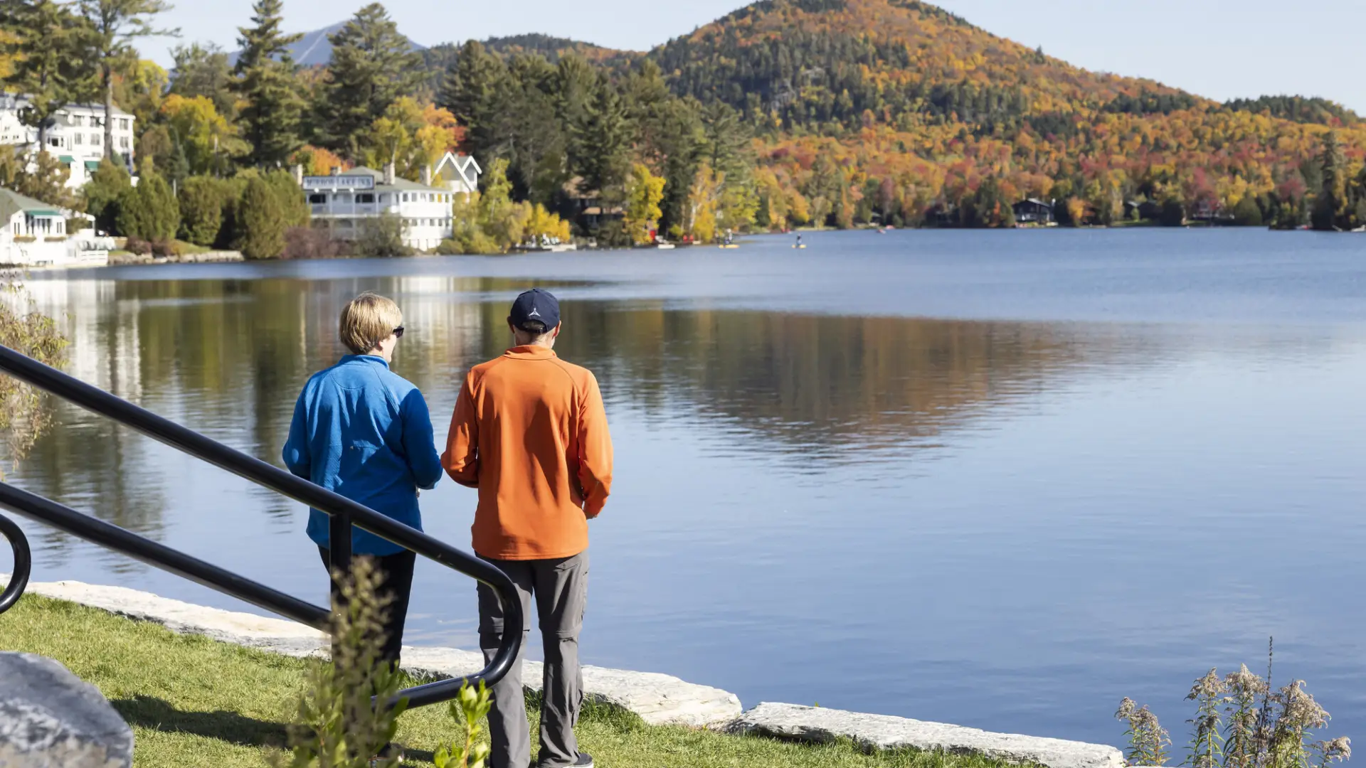 Two people look at the view of a mountain across a lake