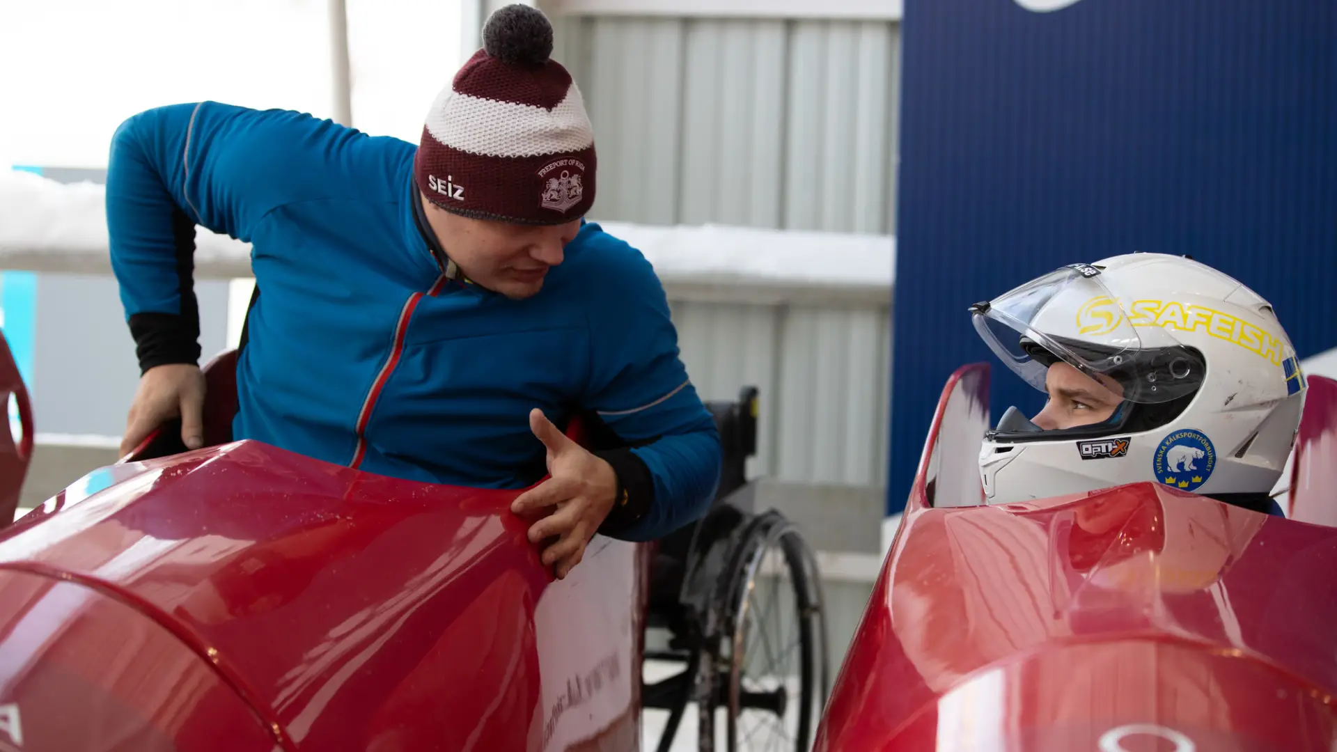 Two adaptive bobsled athletes chat while preparing for a practice run down the Lake Placid bobsled track