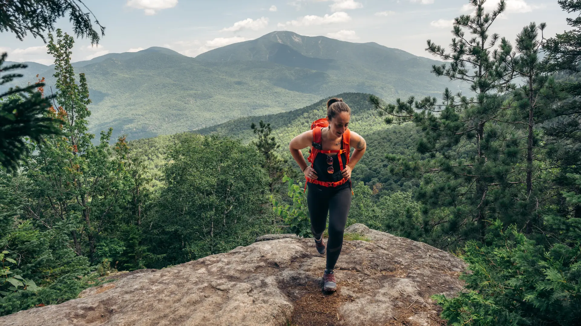 A woman climbs a rocky mountaintop.