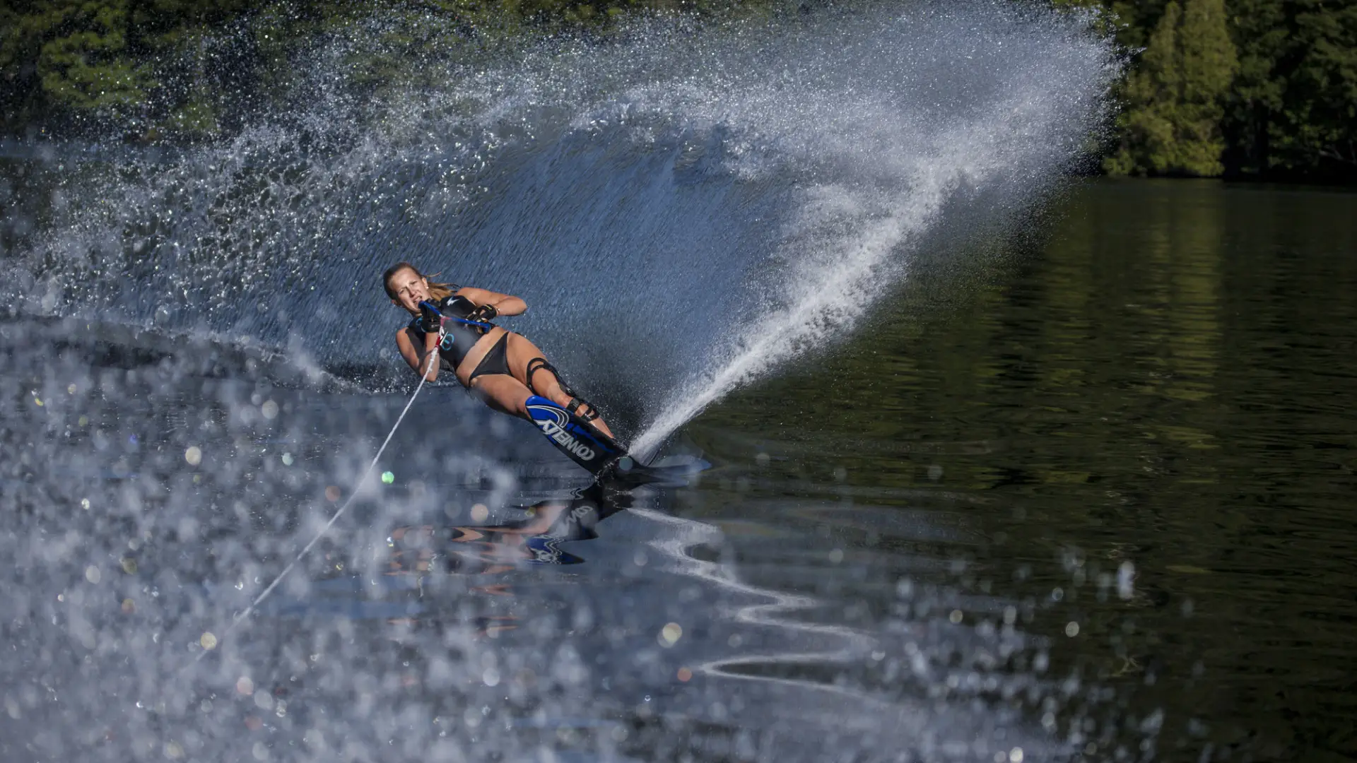 A woman on water skis carves through Lake Placid lake.