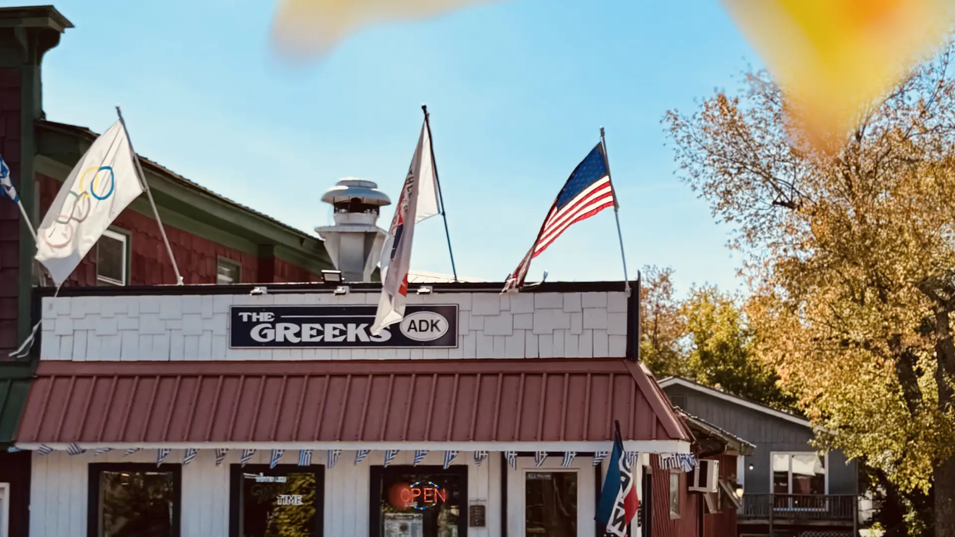 The exterior of The Greeks ADK surrounded by golden fall foliage - open year round!
