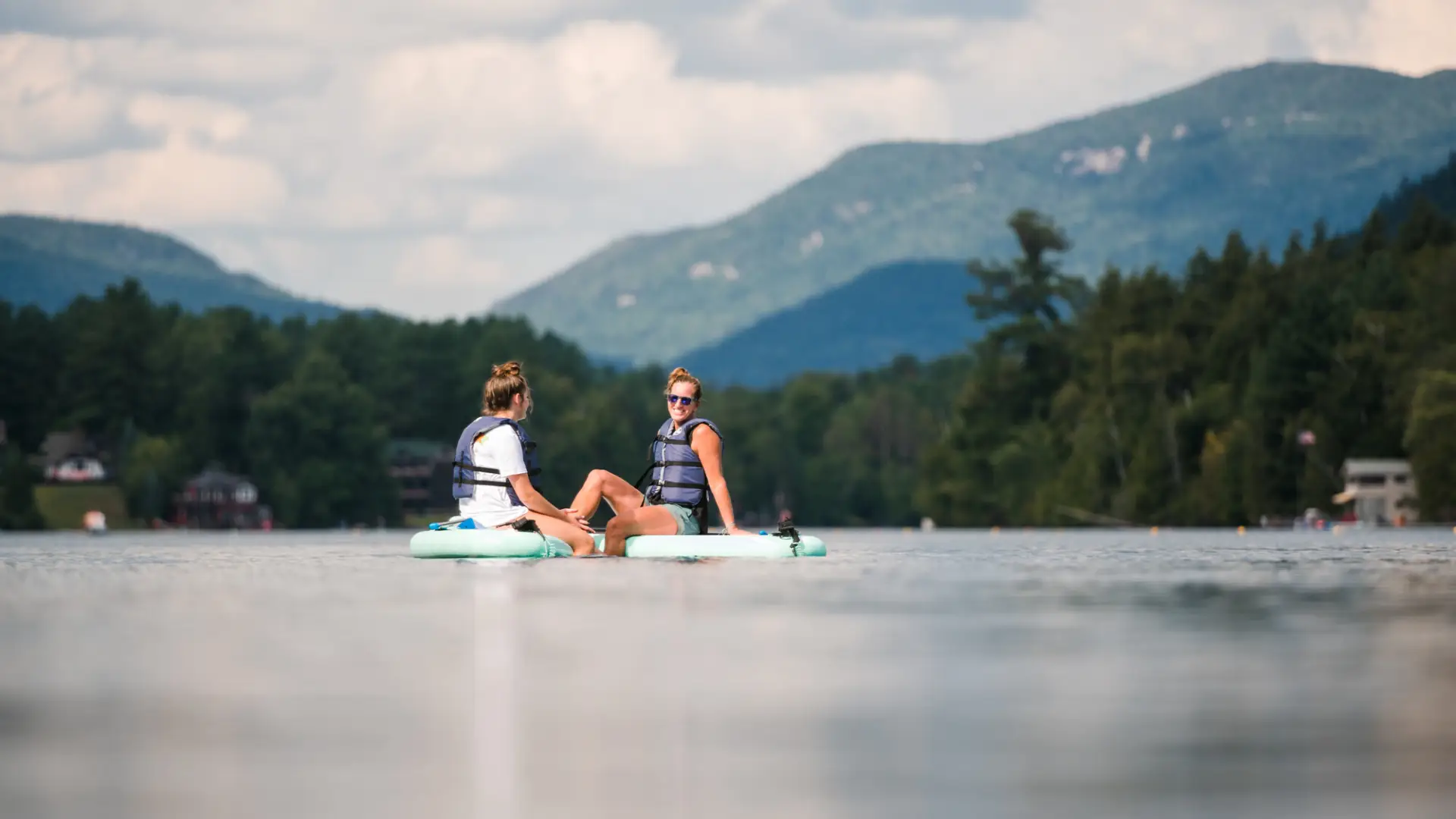 two women chat on SUPs in the middle of Mirror Lake.
