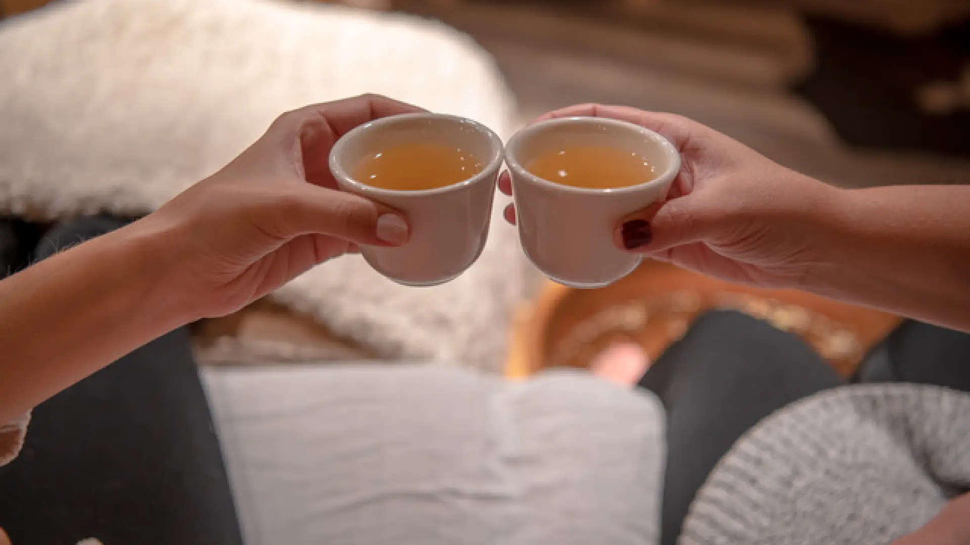 Two friends tink ceramic cups filled with nourishing herbal tea