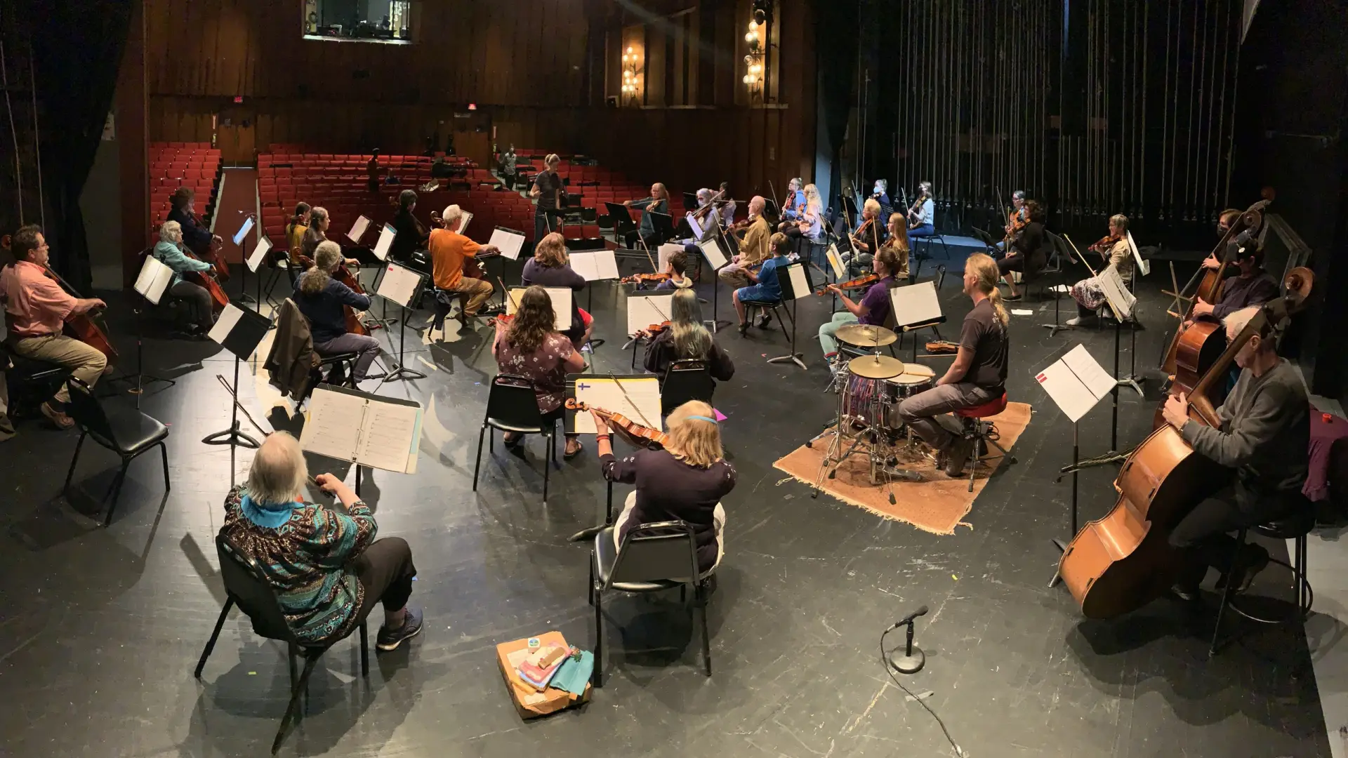 An orchestra on a stage practicing with their instruments.