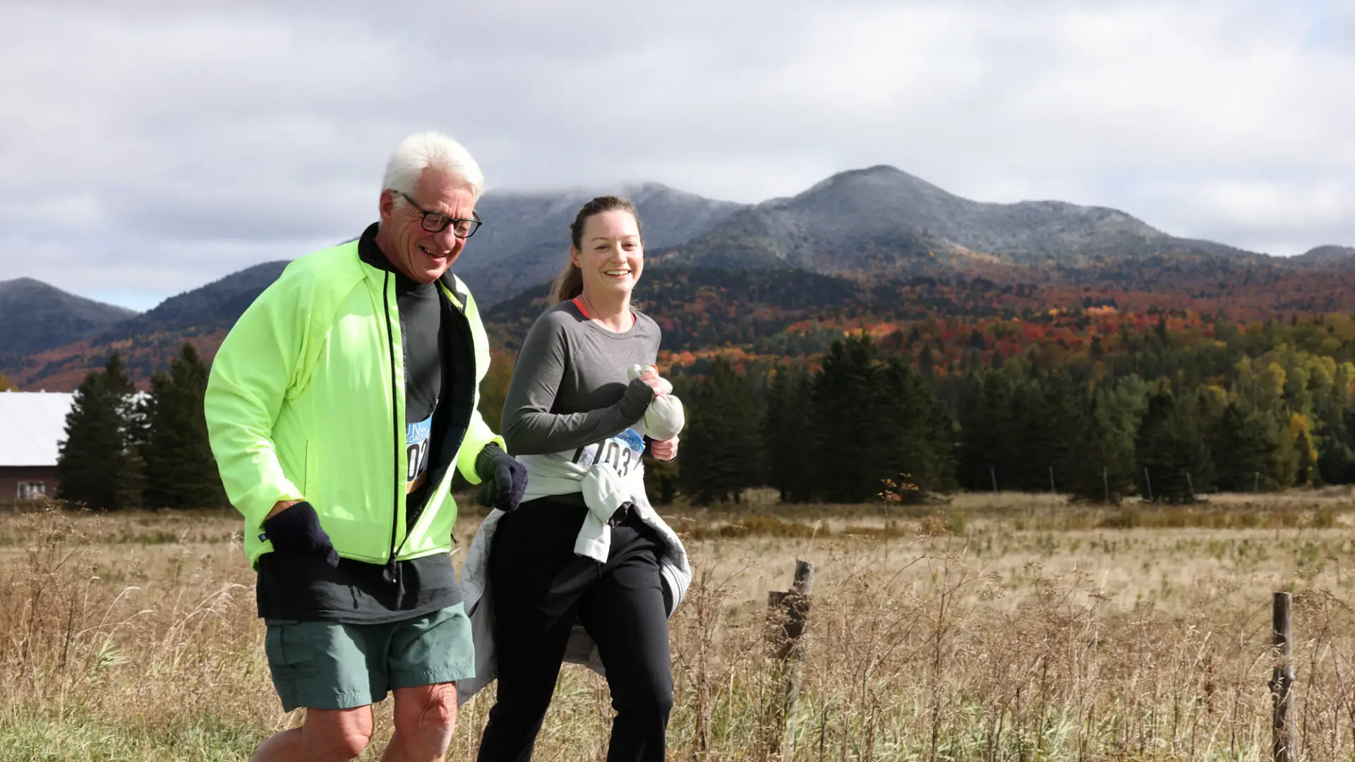 Man and woman running side by side on road with mountain in background