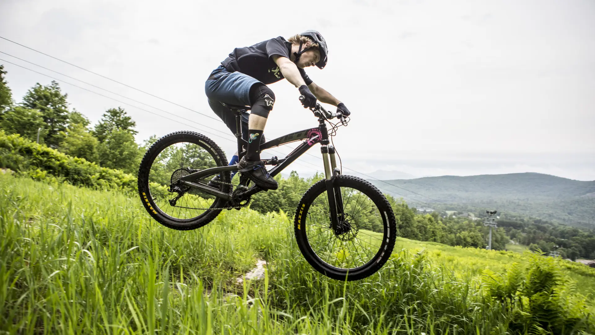 A person on a mountain bike descends a grassy hill.