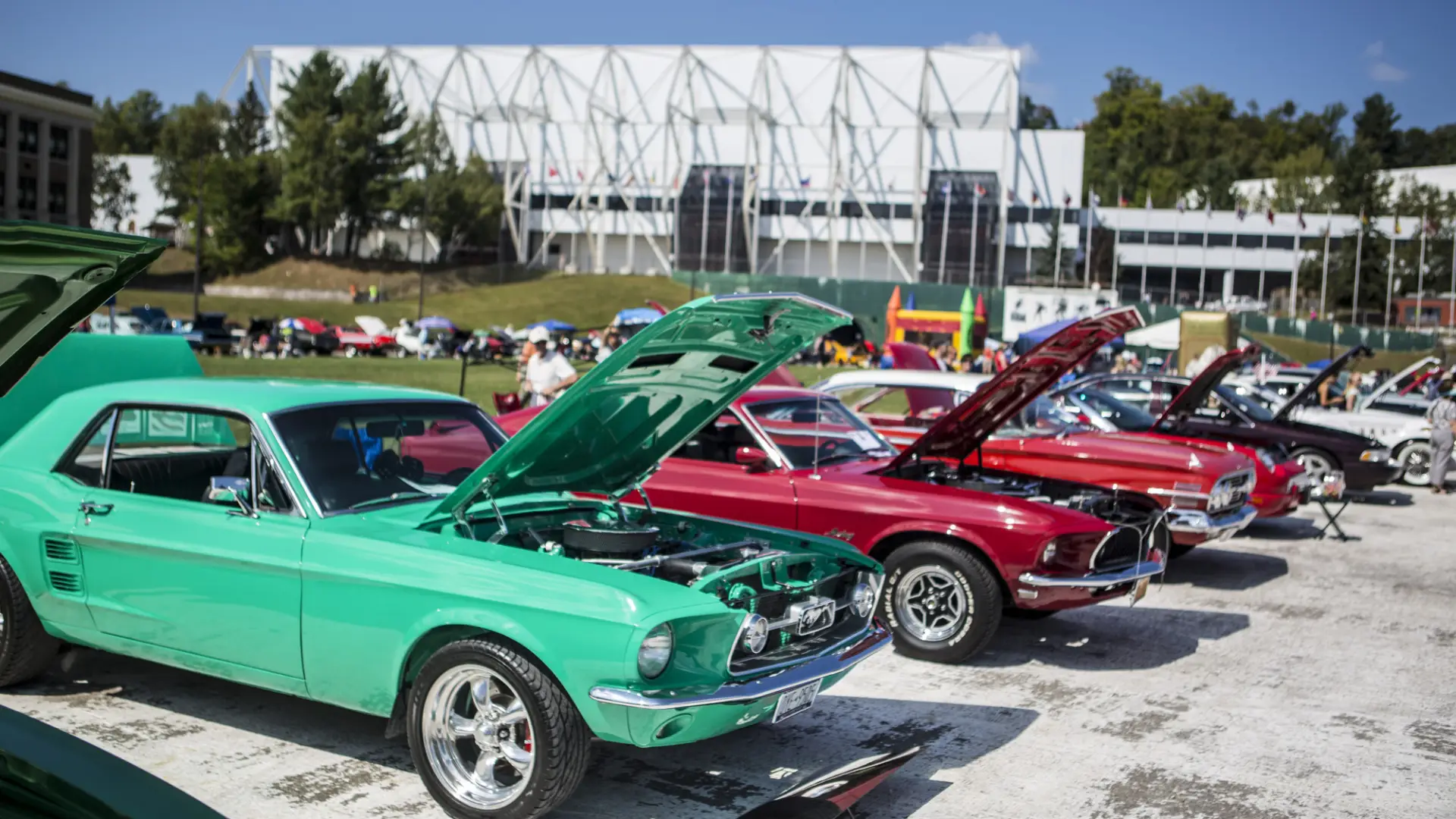 Colorful classic cars parked in a row with their hoods up on Olympic Oval for car show