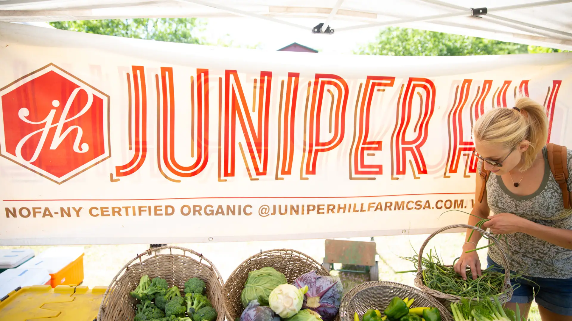 A woman picking out fresh vegetables at a farmers market.