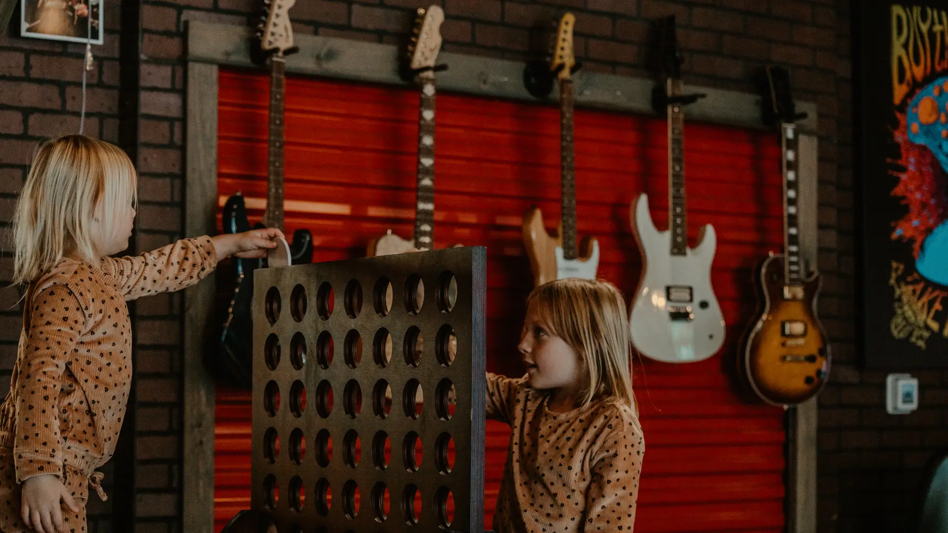 Two girls play giant connect four in front of a wall full of guitars.  Photo Credit to A. Kelly.