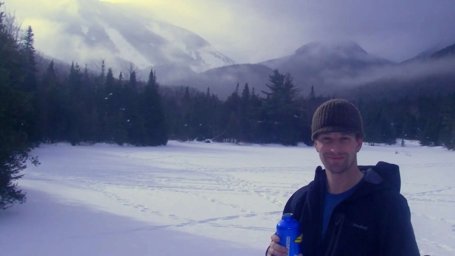 A skier takes a break at Marcy Dam (The terminus of the Whale's Tail Ski Trail)