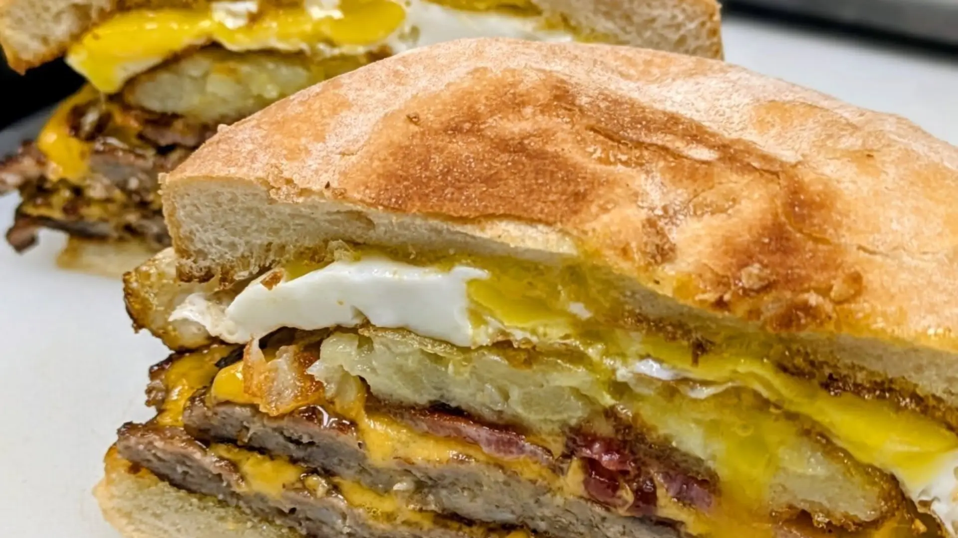 A cross-section cut of double smashburger topped with pickles and fried egg.