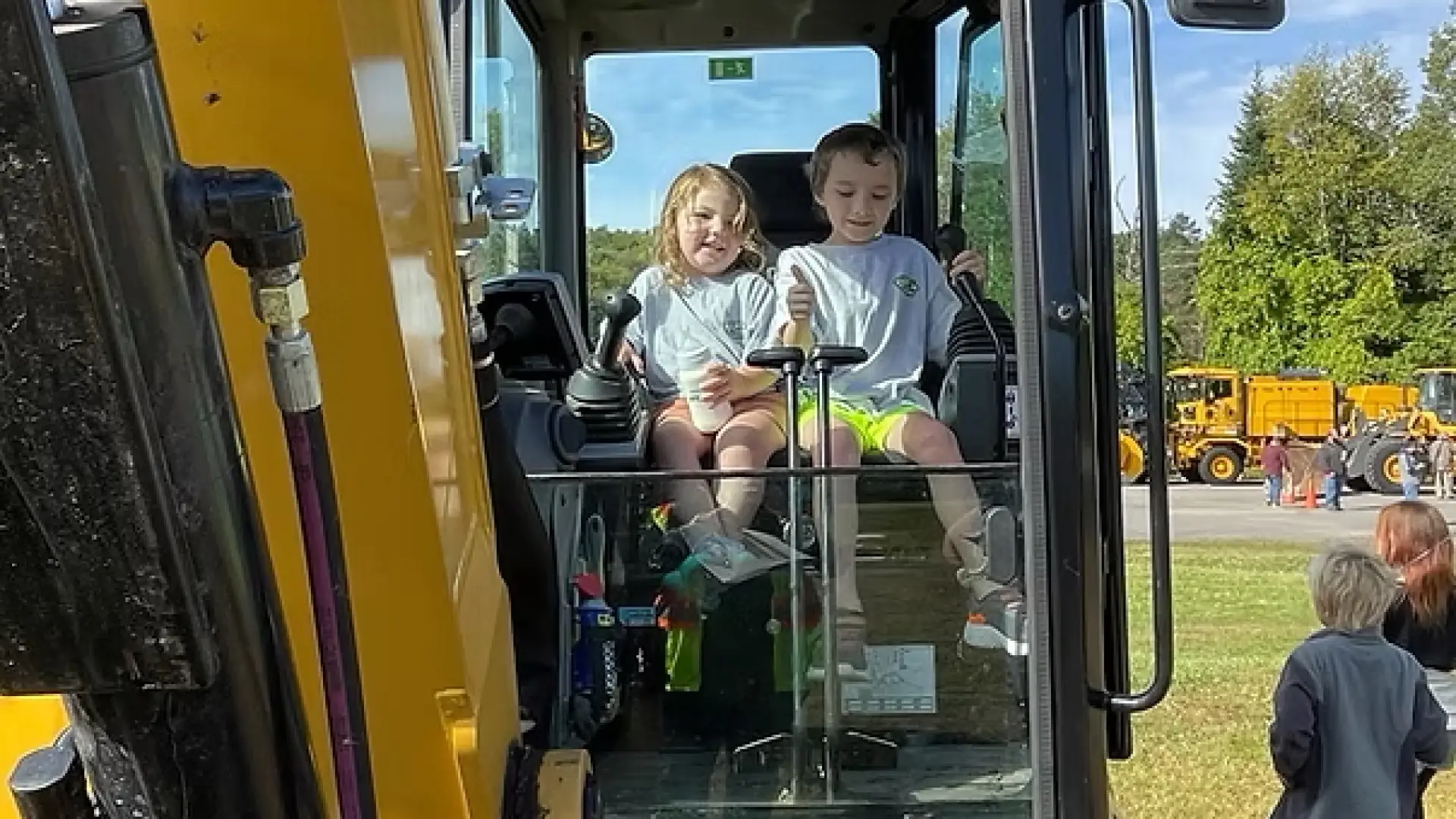 children sitting on yellow heavy machine