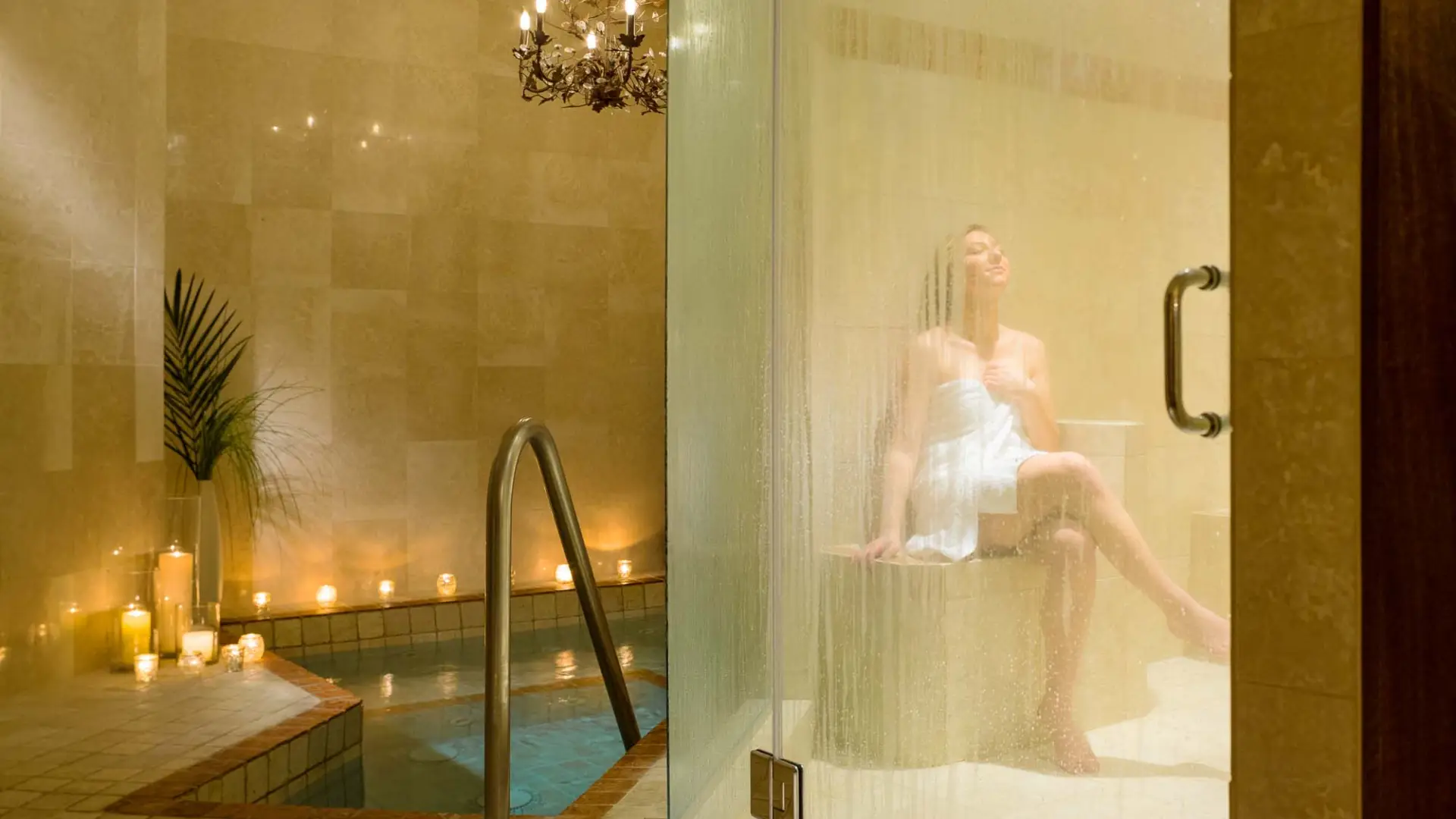 A woman sits wrapped in a lush towel while basking in the rejuvenating steam room.