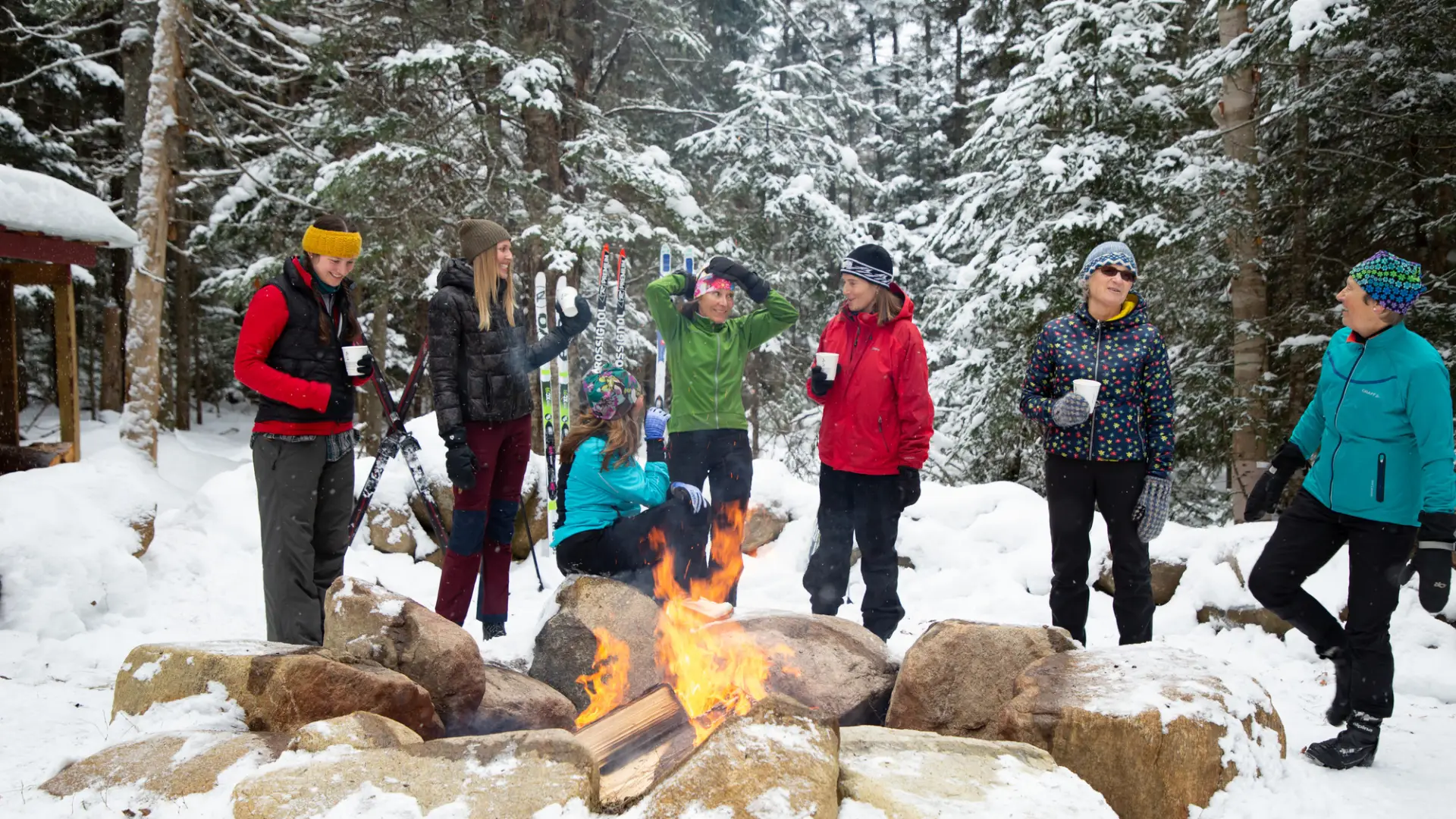 Group of women stand around fire in the snow