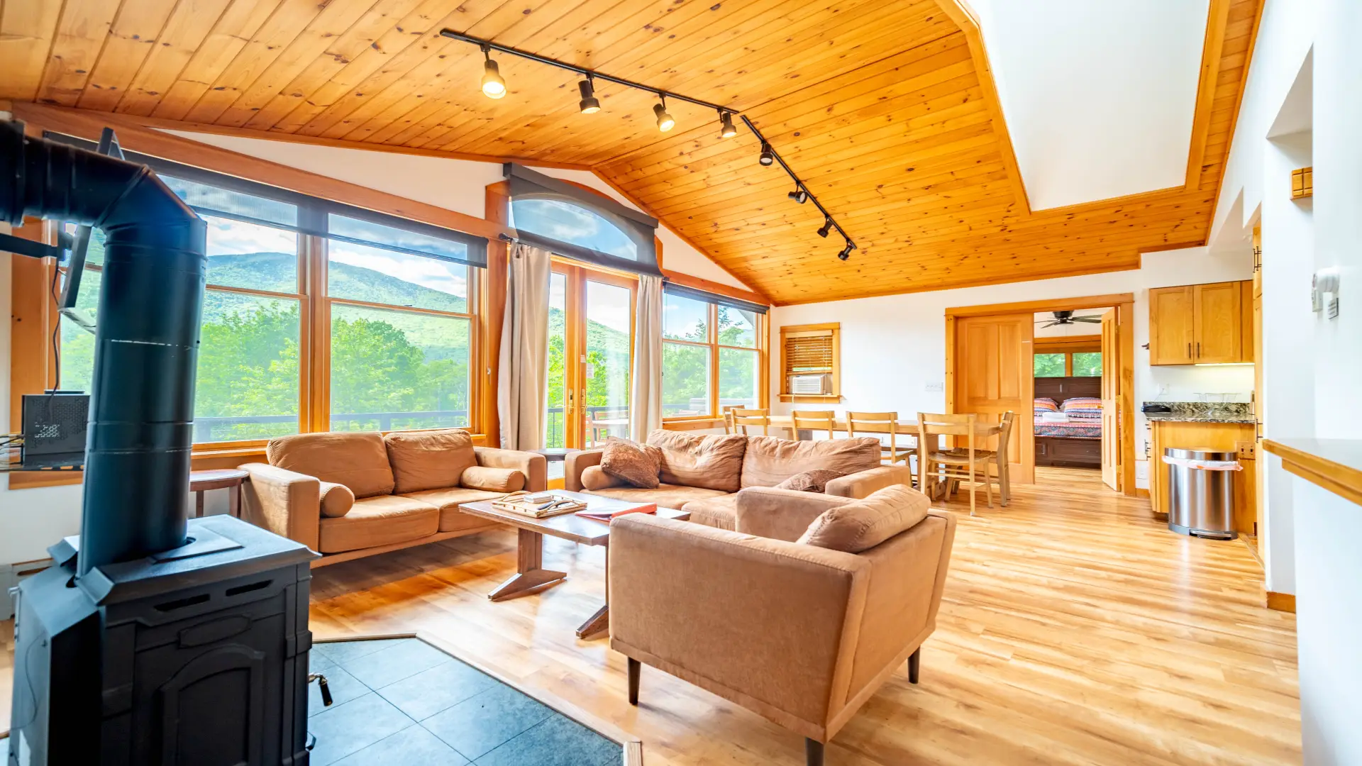 Interior Great Room with comfy couches, a wood stove and knotty pine paneling throughout