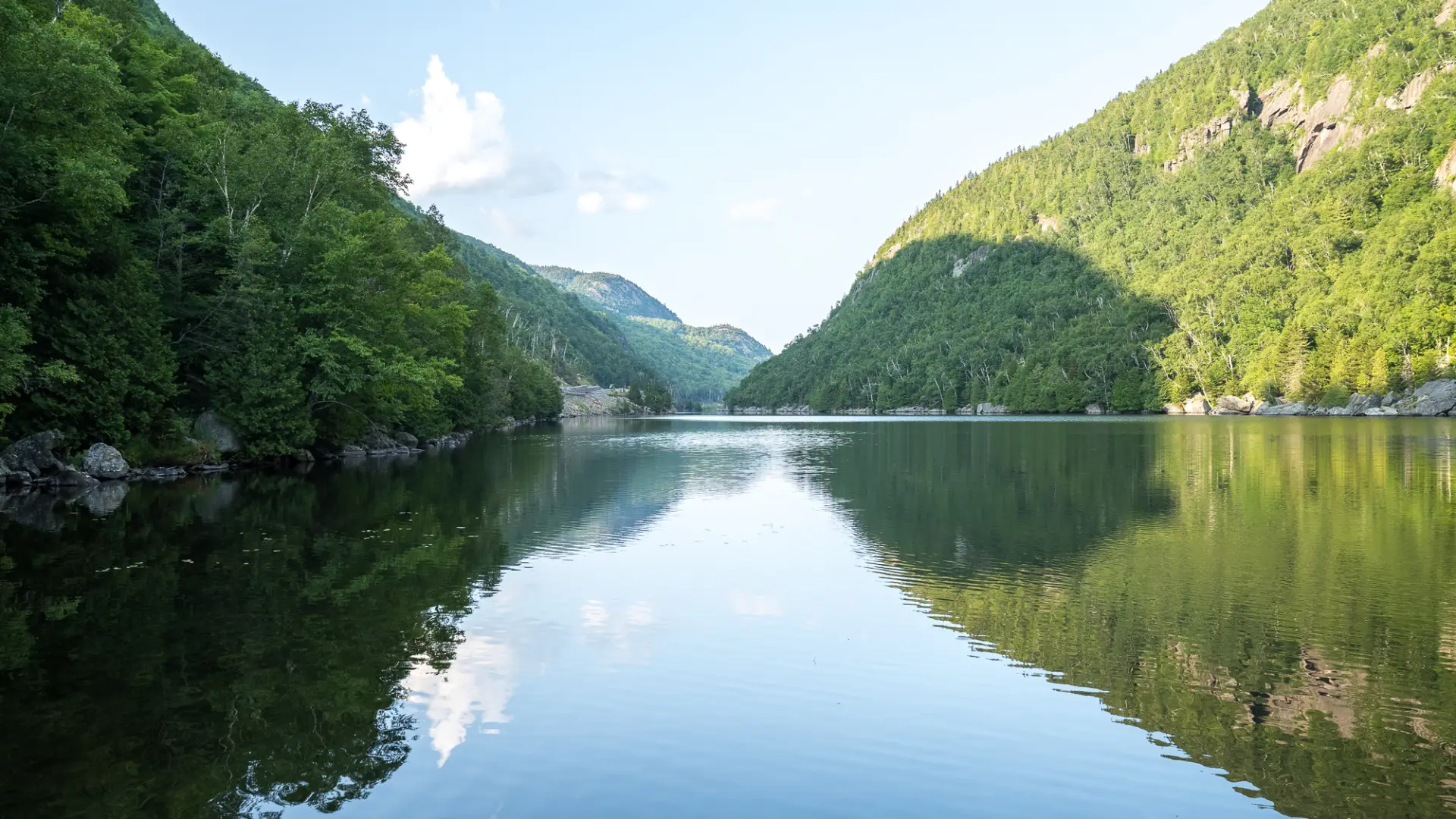 The peaceful waters of an Adirondack lake with dramatic cliffs on each side.