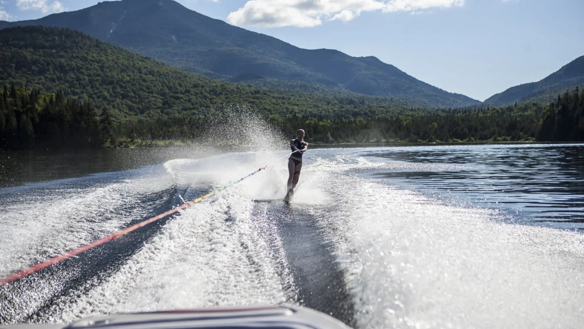 A woman waterskis on Lake Placid with mountains in the background.