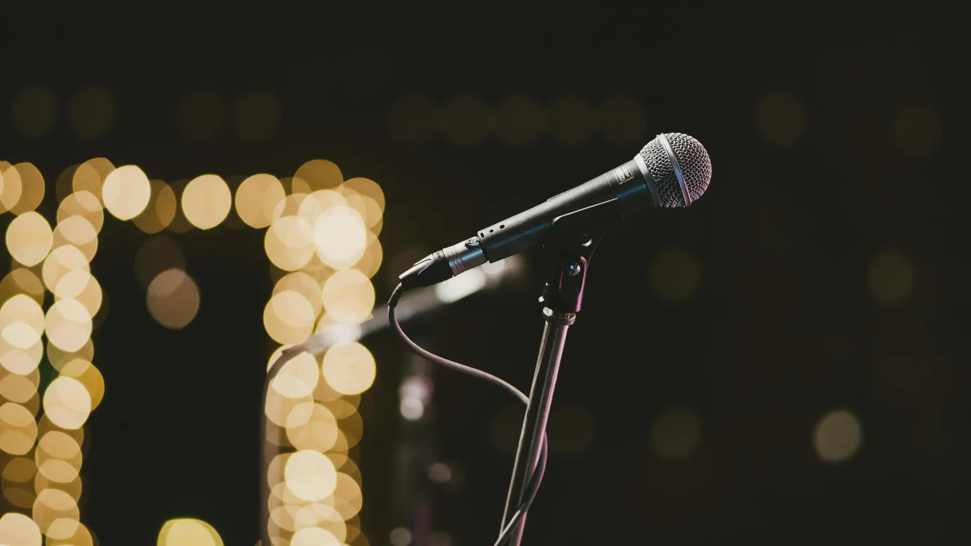 Stock image of microphone on stand with glowing lights in background