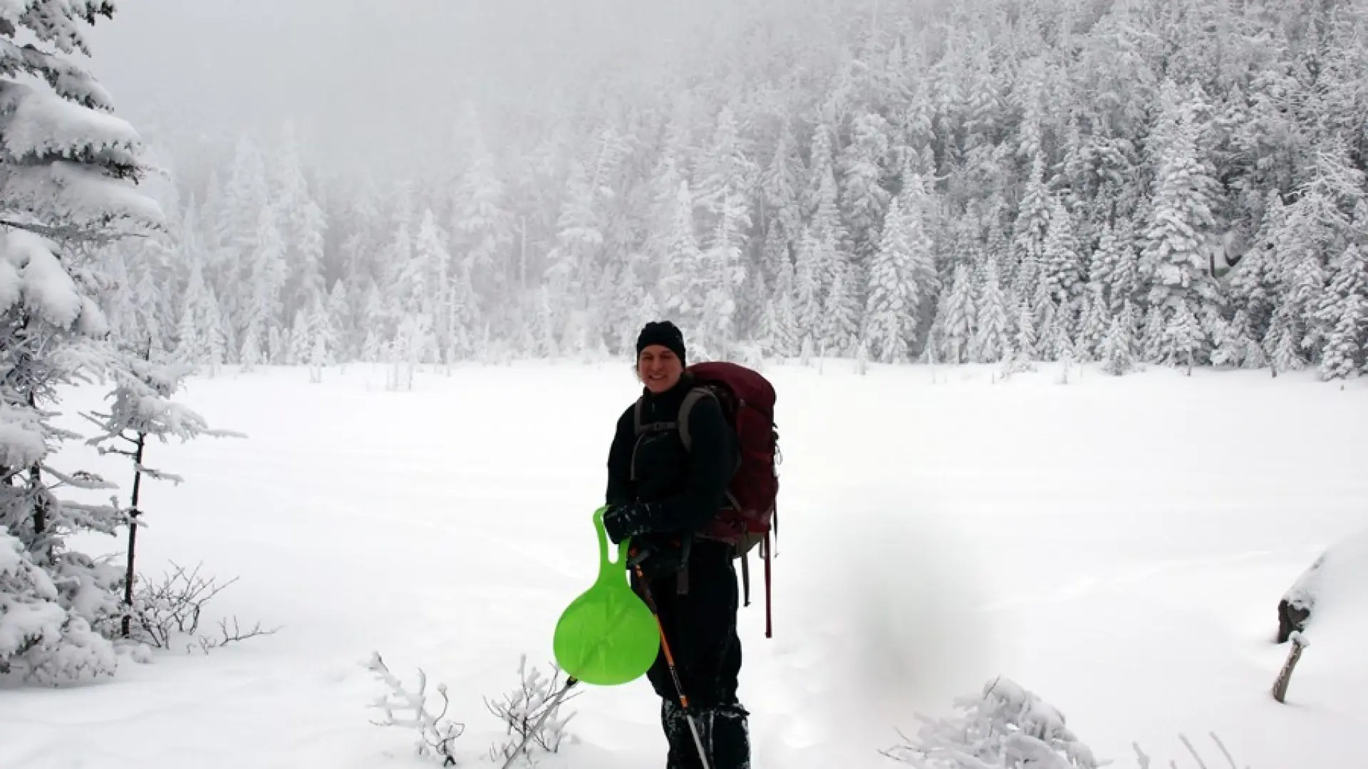 A hiker standing by a frozen pond