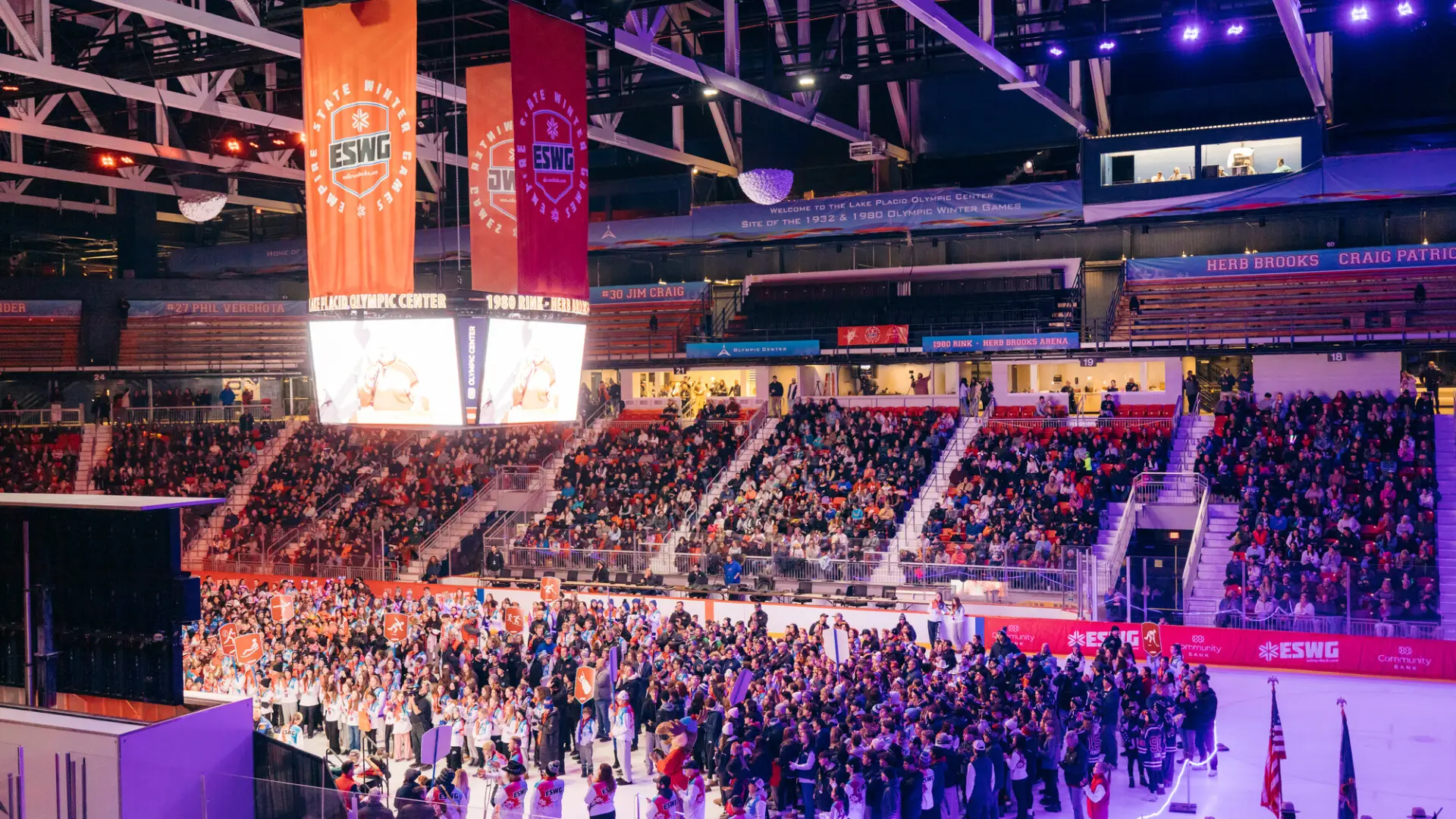 A wide-angle, high angle shot of a crowded indoor ice arena during the opening ceremony of the 2025 Empire State Winter Games (ESWG)