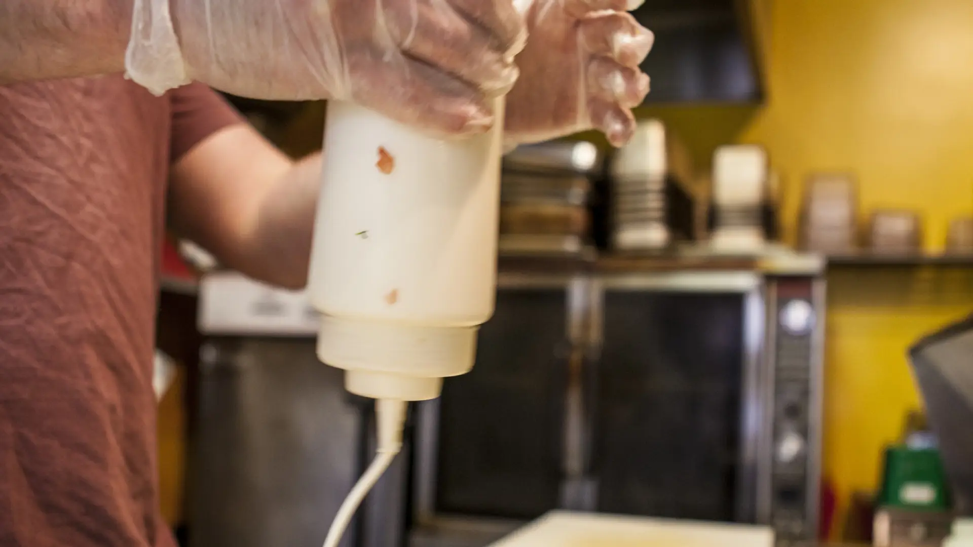 A man pours sour cream on a burrito.
