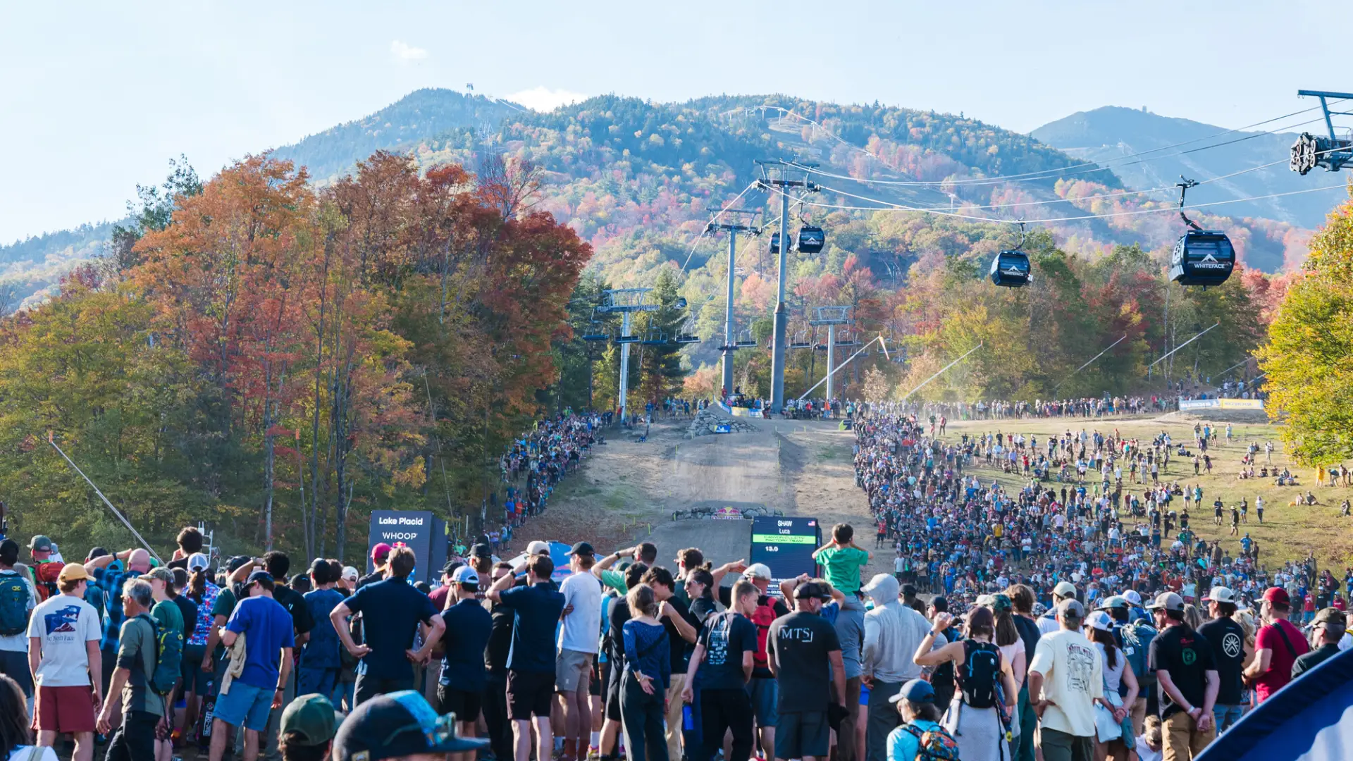 Large crowd gathered at finish line area of 2025 WHOOP UCI MTB Downhill World Cup at Whiteface Mountain with slopes behind