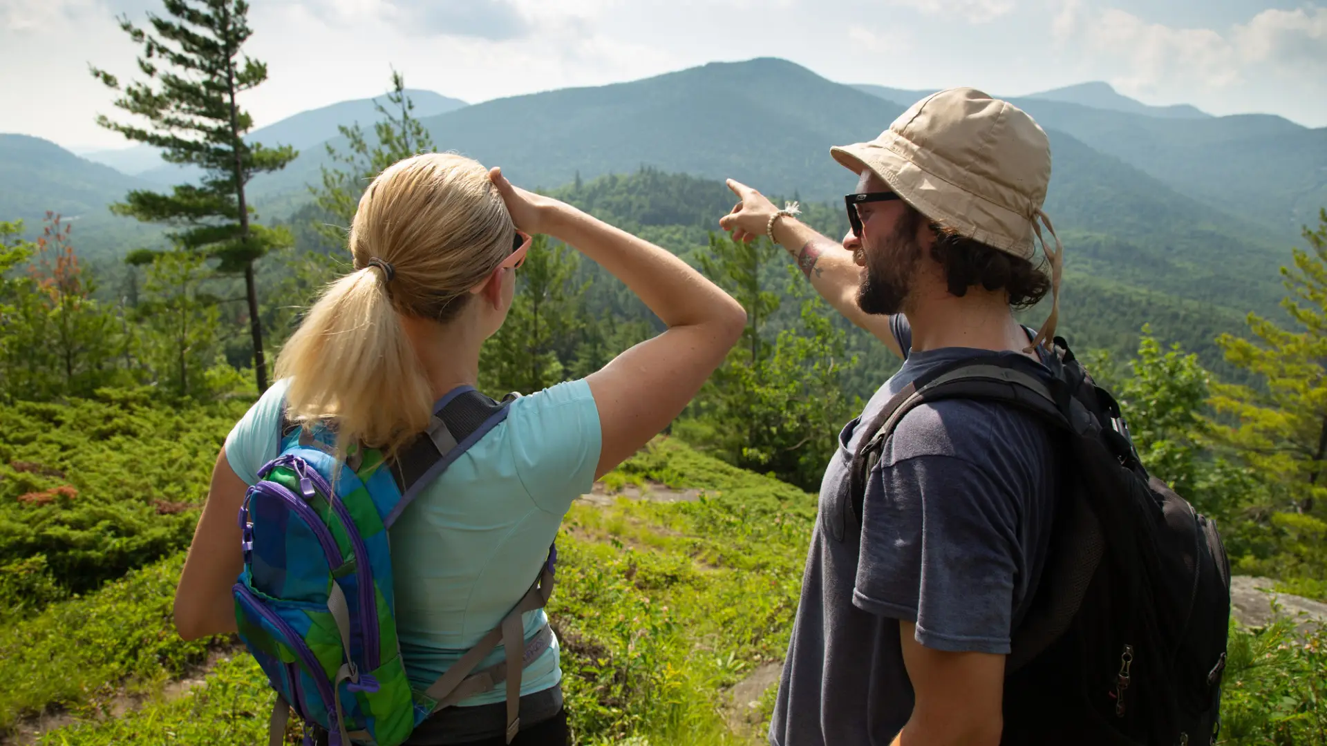 A man shows a woman the view of a mountain in the distance.
