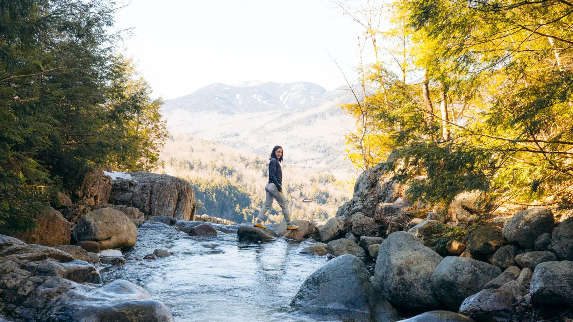 A woman walks across a waterfall. 