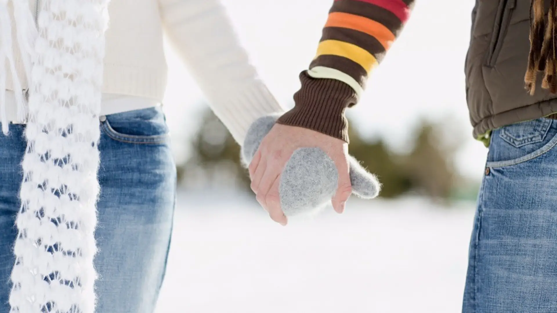 Two mittened hands walk through a snowy meadow