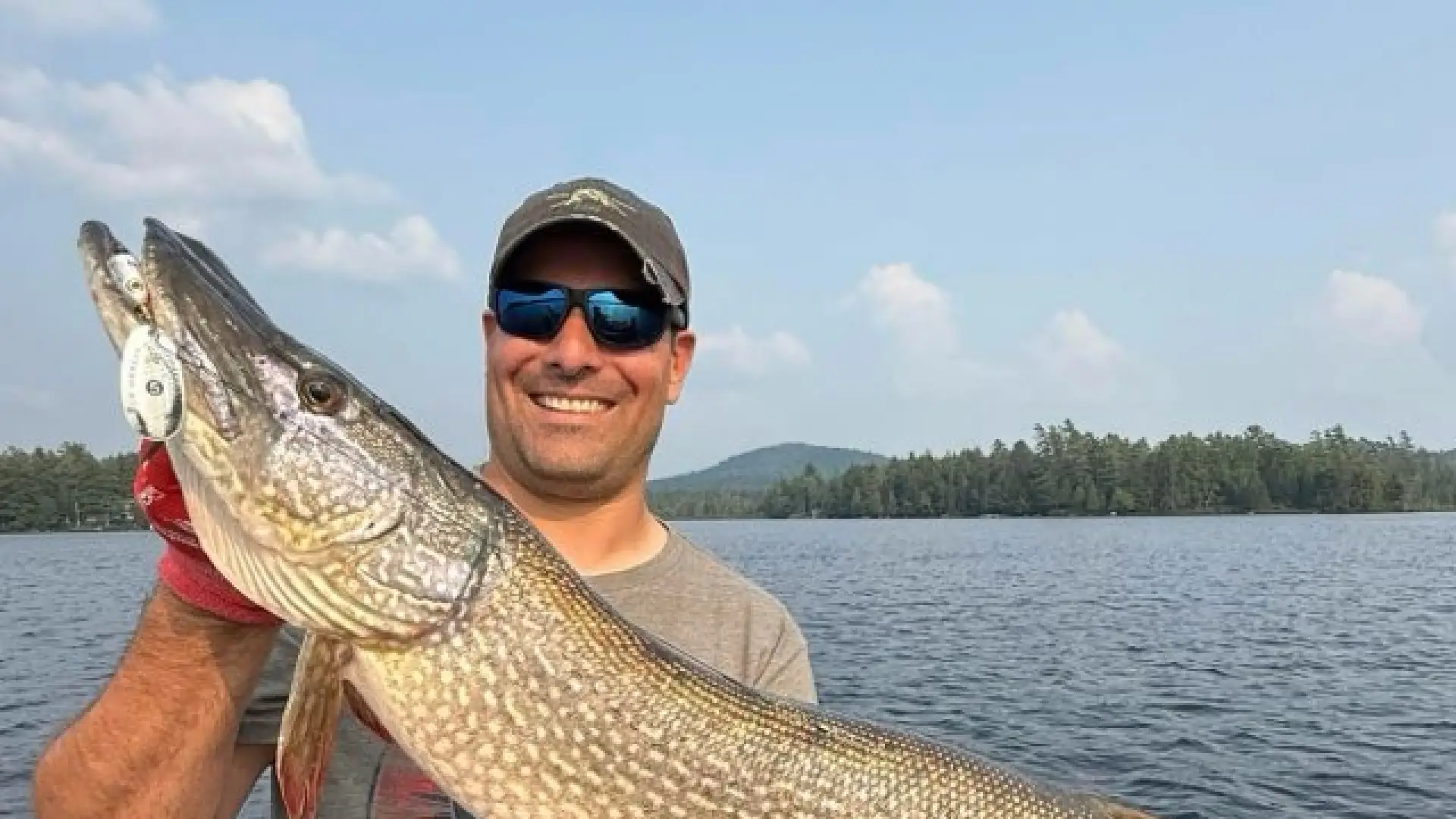 A smiling man holds a huge pike