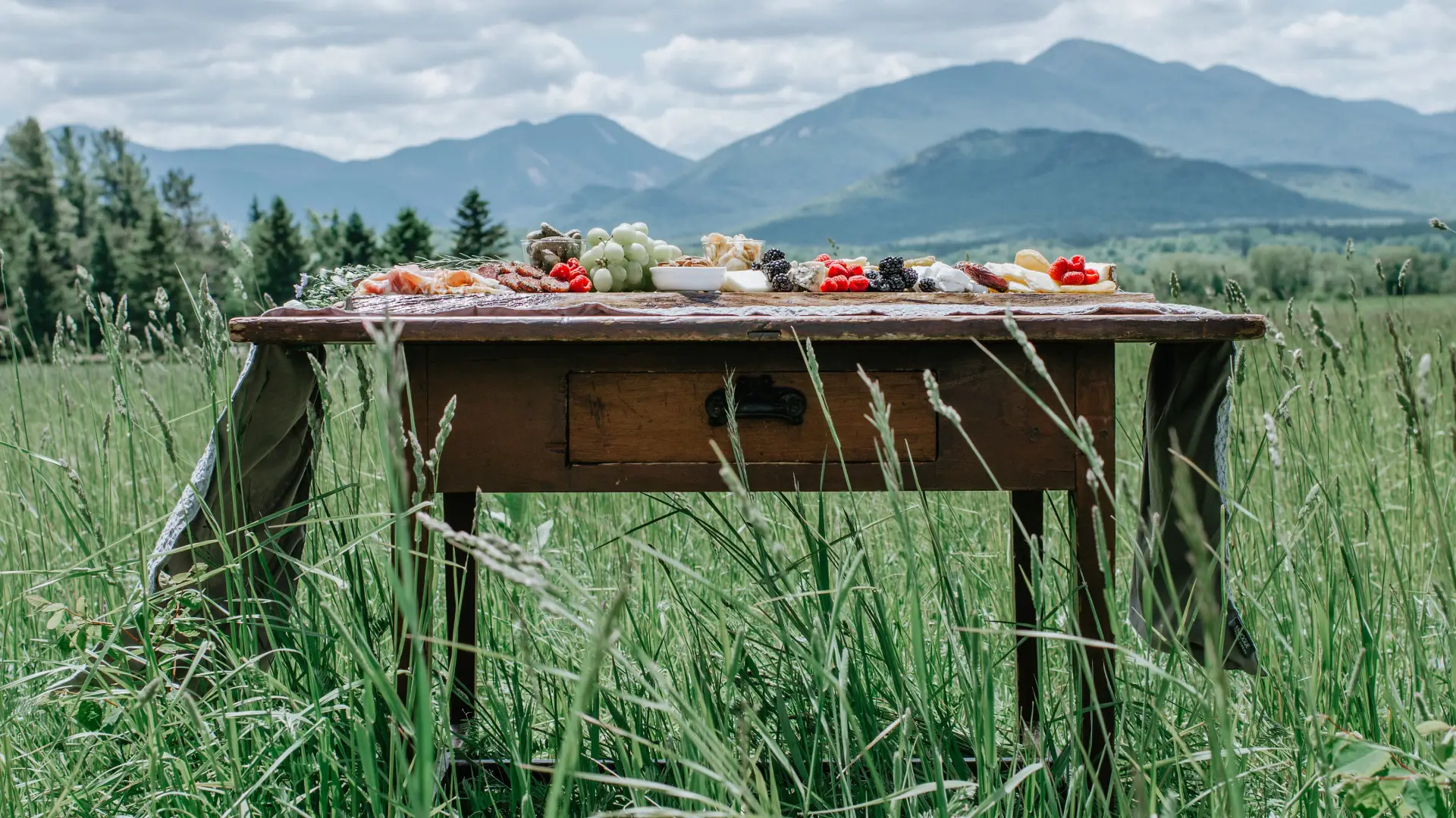 antique desk with flowers in the meadow with the high peaks in the background