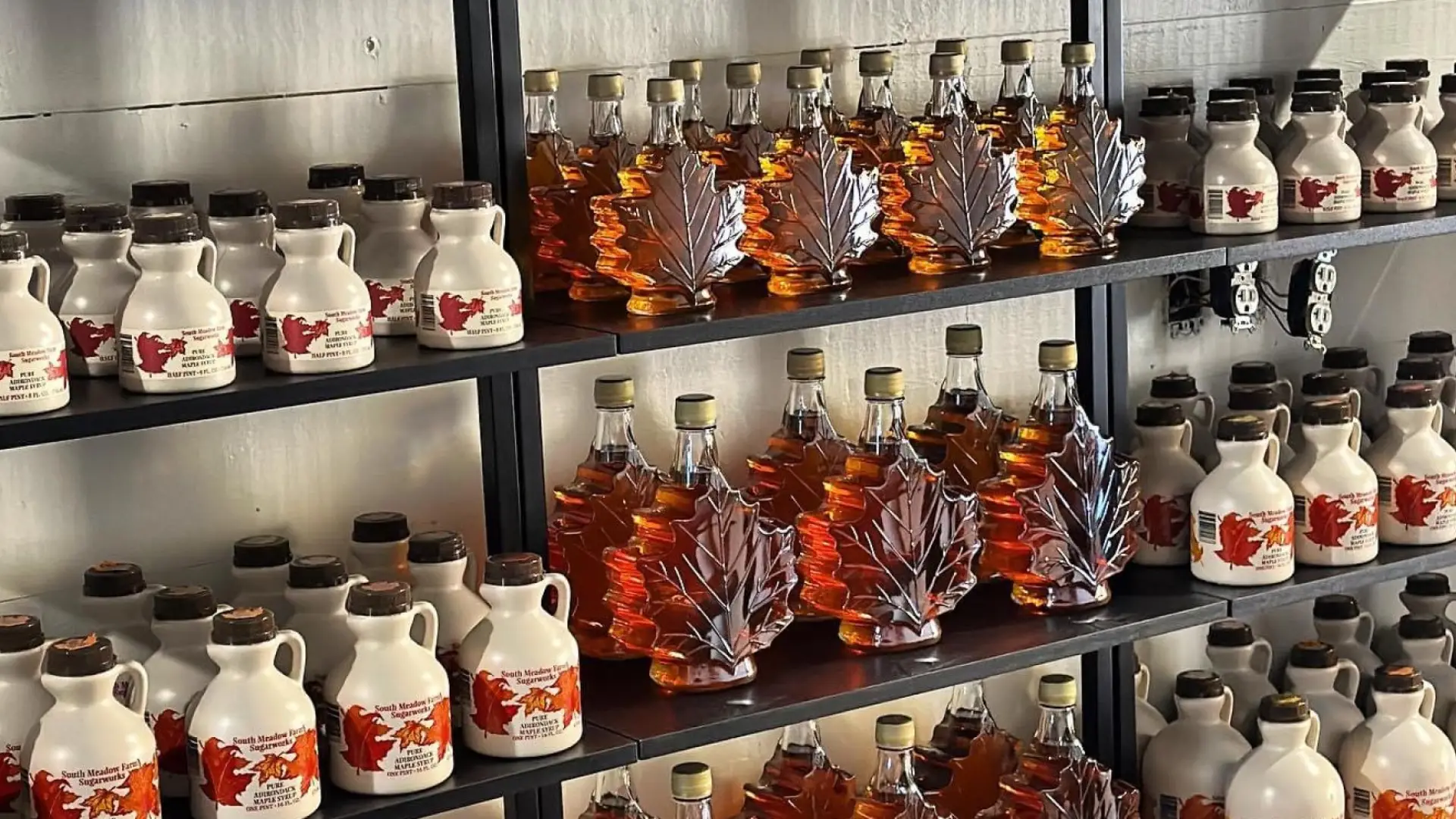 Store shelves stocked with plastic and glass containers of maple syrup