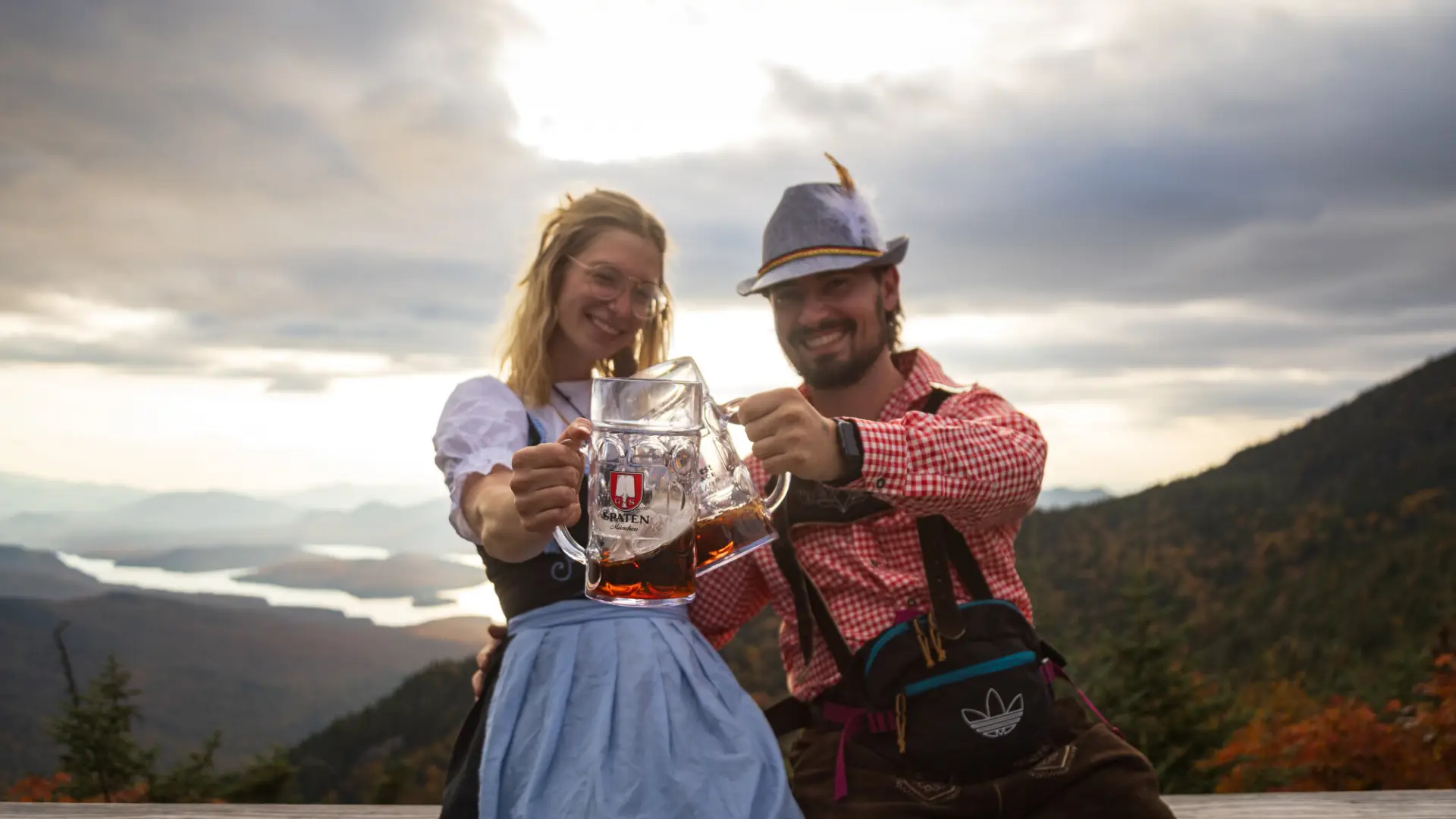 A man and woman cheers mugs at an Oktoberfest.