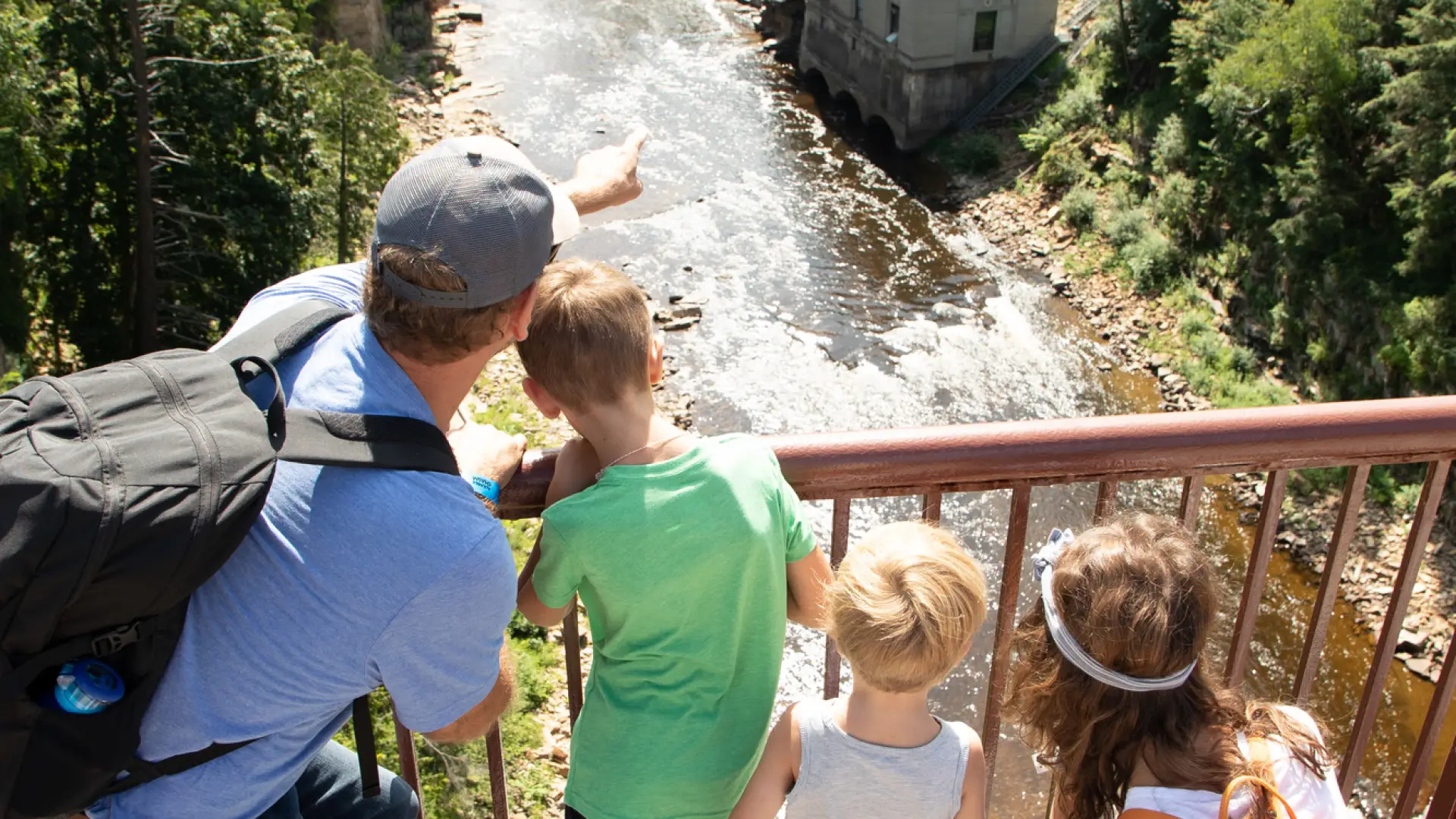 A man points to Ausable Chasm with his children.