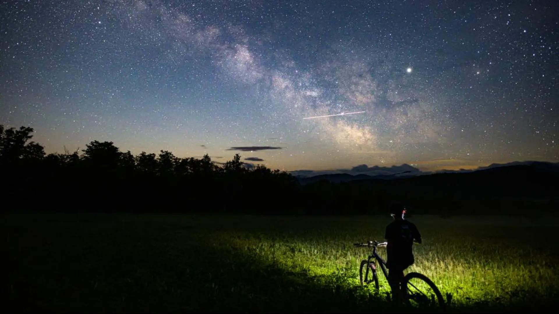 A mountain biker with a headlamp at night