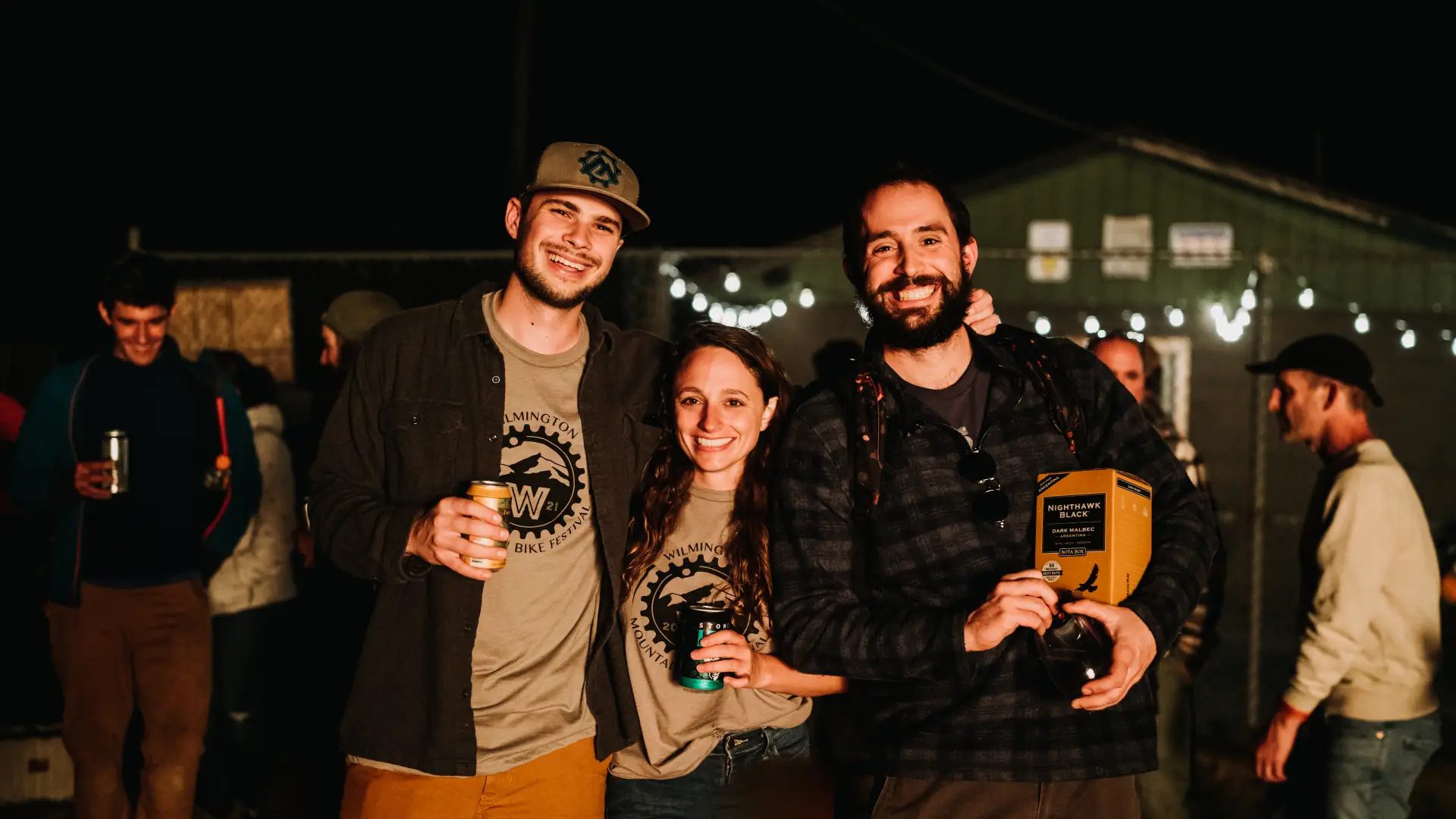 Three people at party wearing BETA shirts smiling and holding drinks