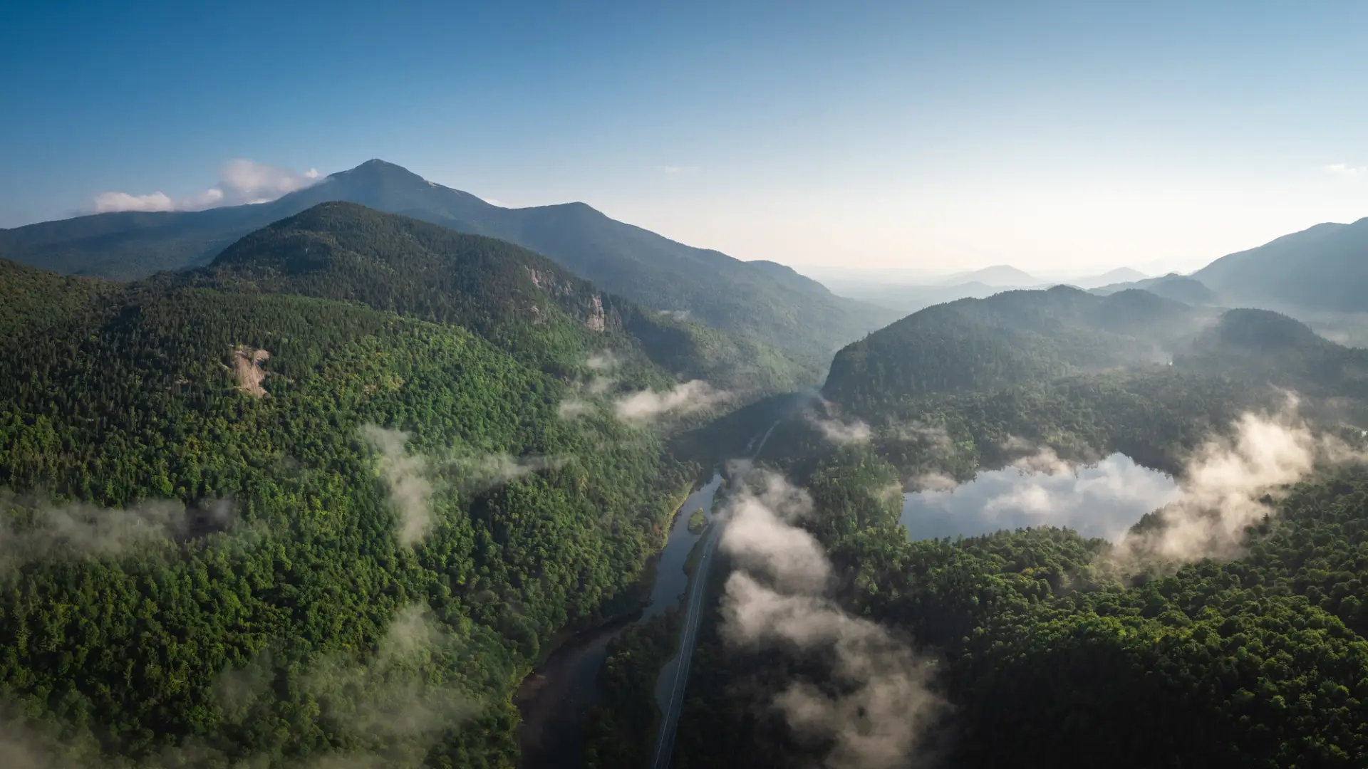 An aerial view of a mountainous area with a road running through it.