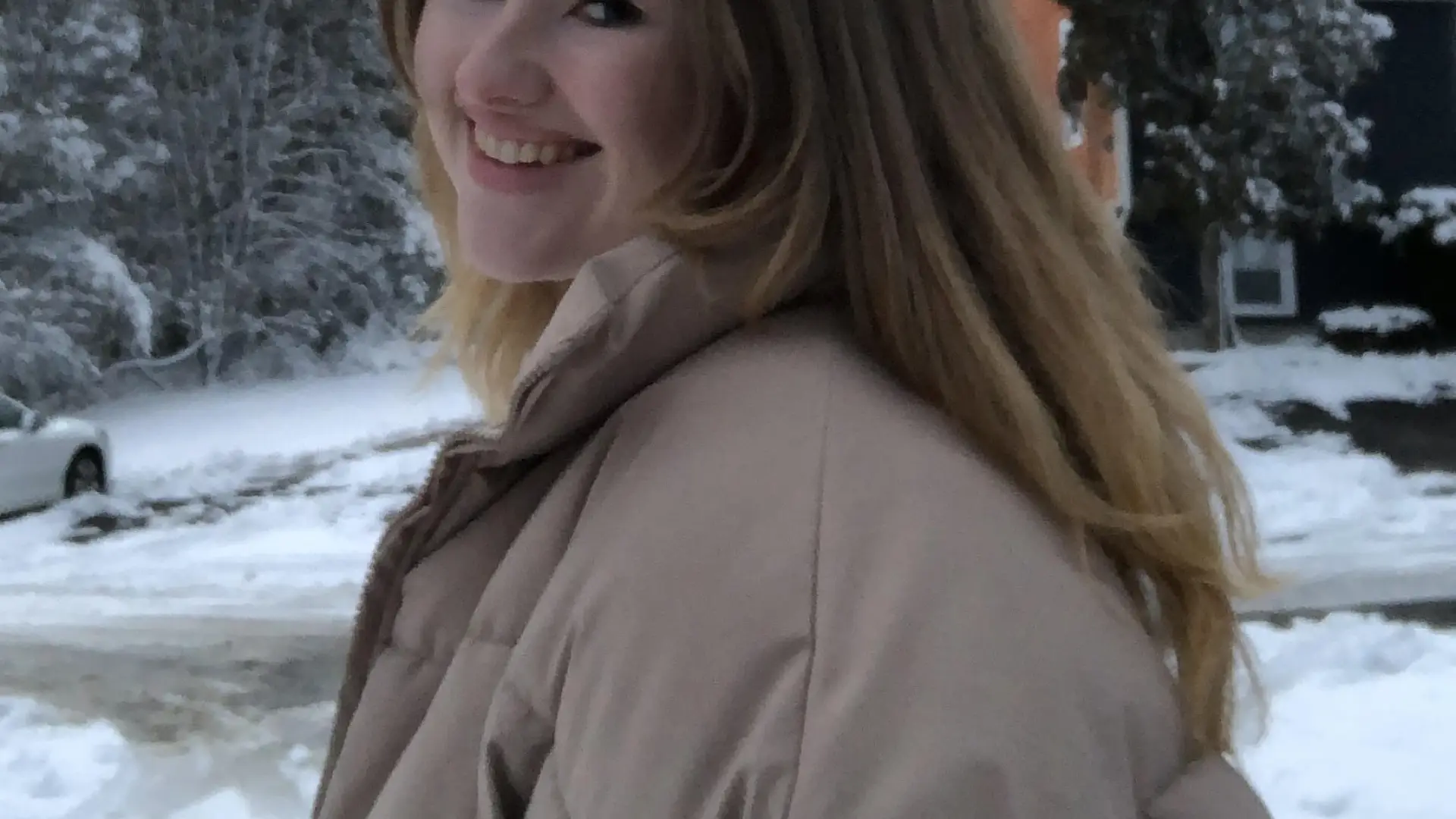 A woman smiles at the camera in a snowy image. 