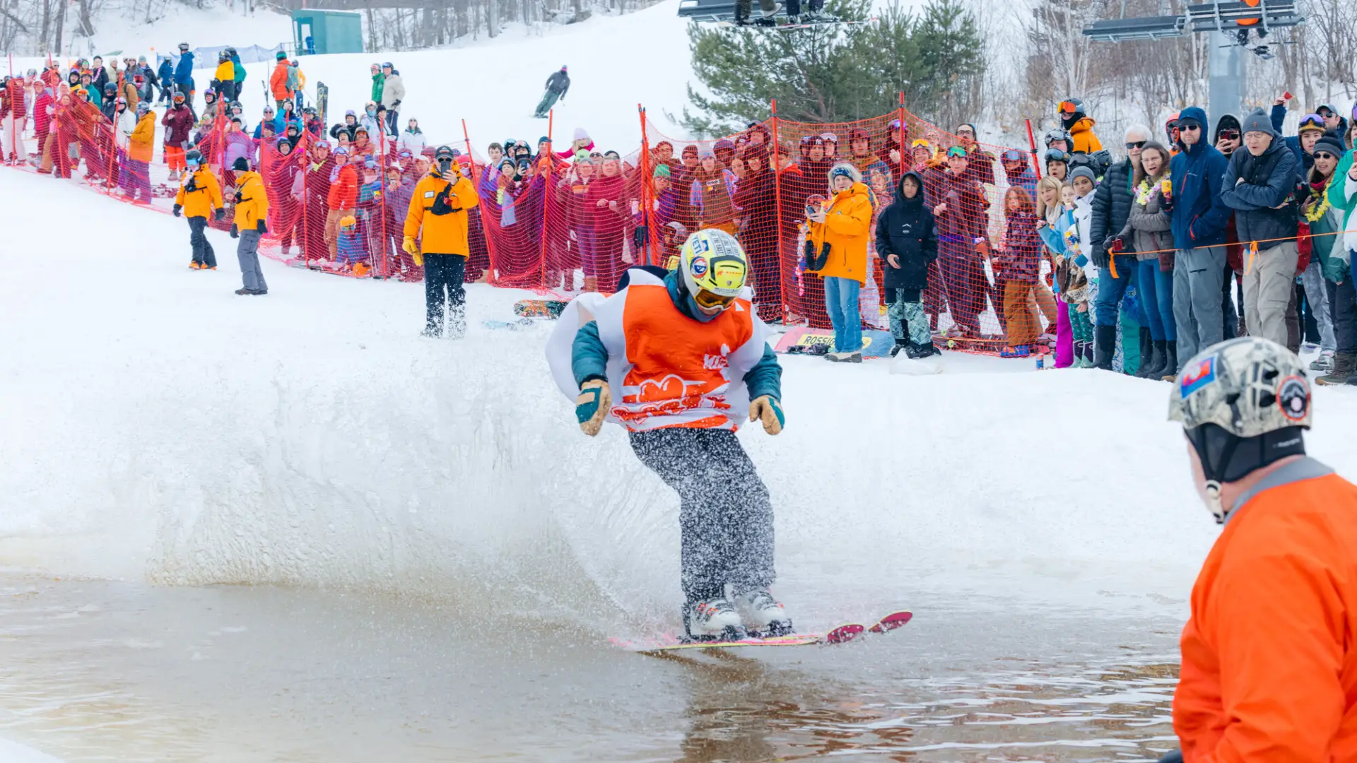 A man in spring ski gear pond skims on snow.