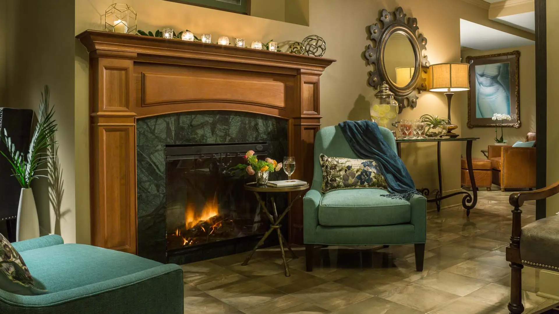 The luxurious women's lounge decorated with a robust fireplace, comfortable chairs, and candle light.